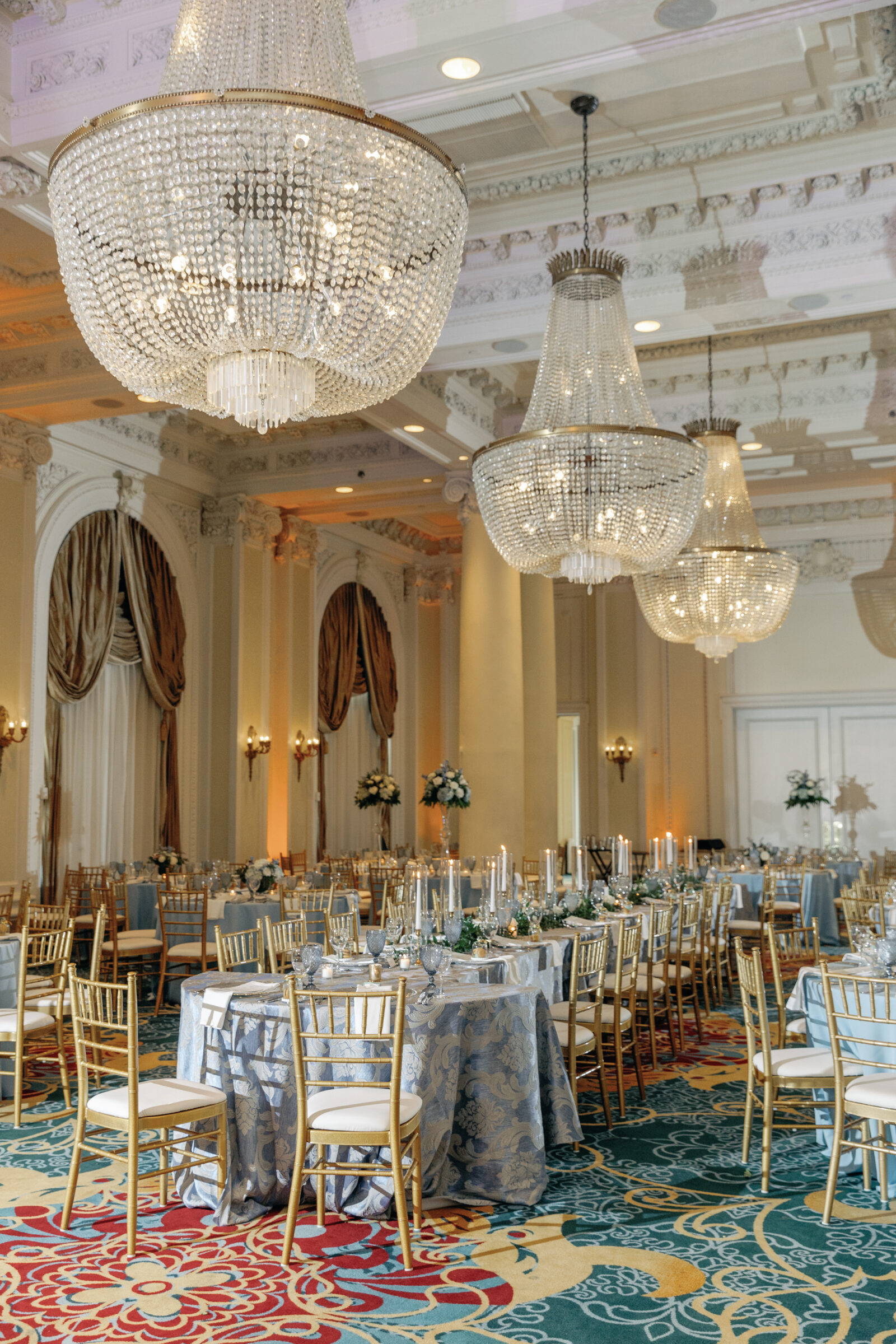 Jefferson Hotel Ballroom Wedding Reception | blue patterned tablecloths and gold chivari chairs make up reception decor in the iconic Jefferson Hotel, one of the best wedding venues in downtown Richmond VA. A row of crystal chandeliers, large arched windows, and intricate tray ceiling details add to the beauty of the wedding reception decor.