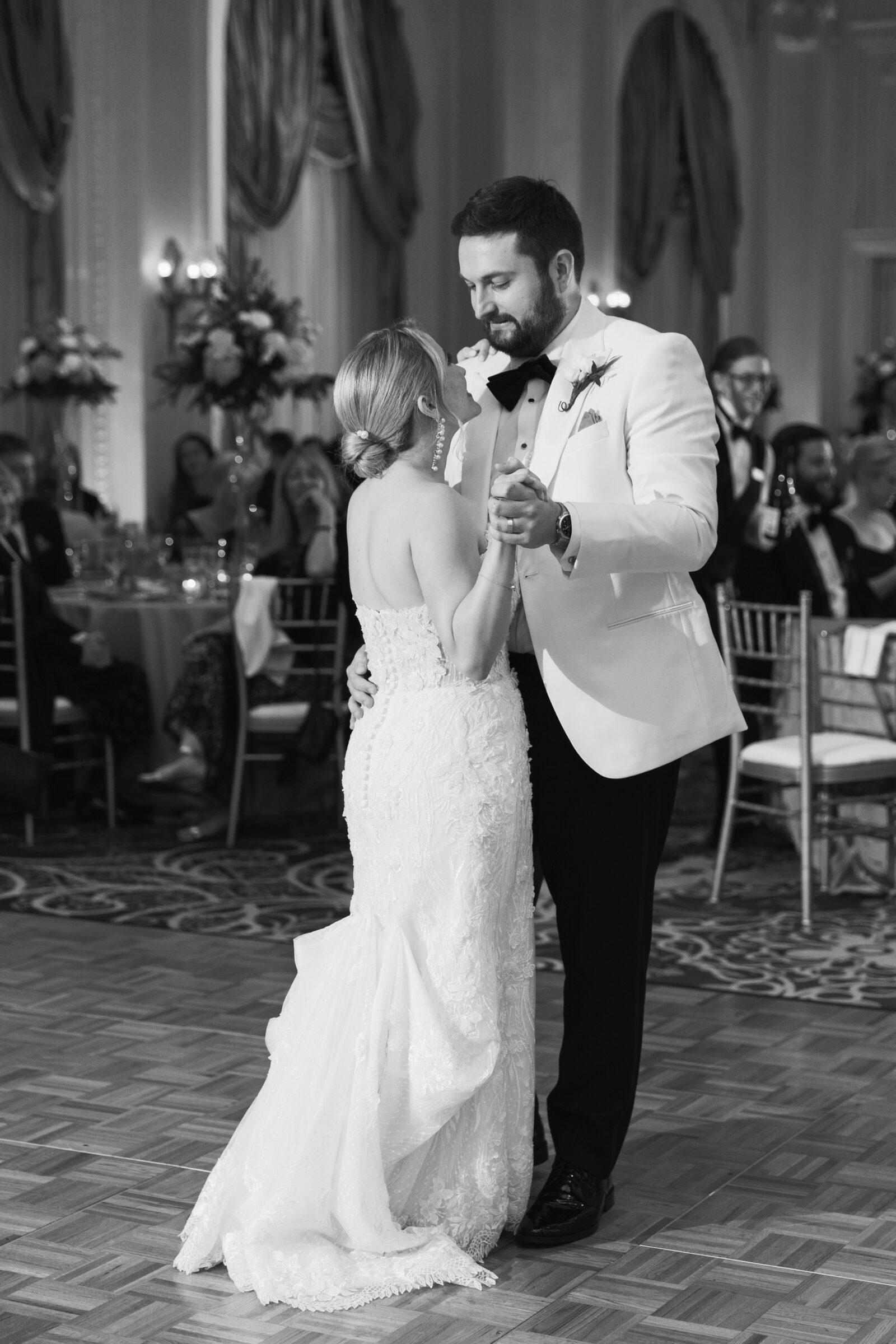 Jefferson Hotel Wedding | A black and white image of a bride and groom sharing their first dance in the ballroom of the Jefferson Hotel, one of the best wedding venues in downtown Richmond. The bride wears a white strapless gown, while the groom sports a white jacket with black pants and bow tie.