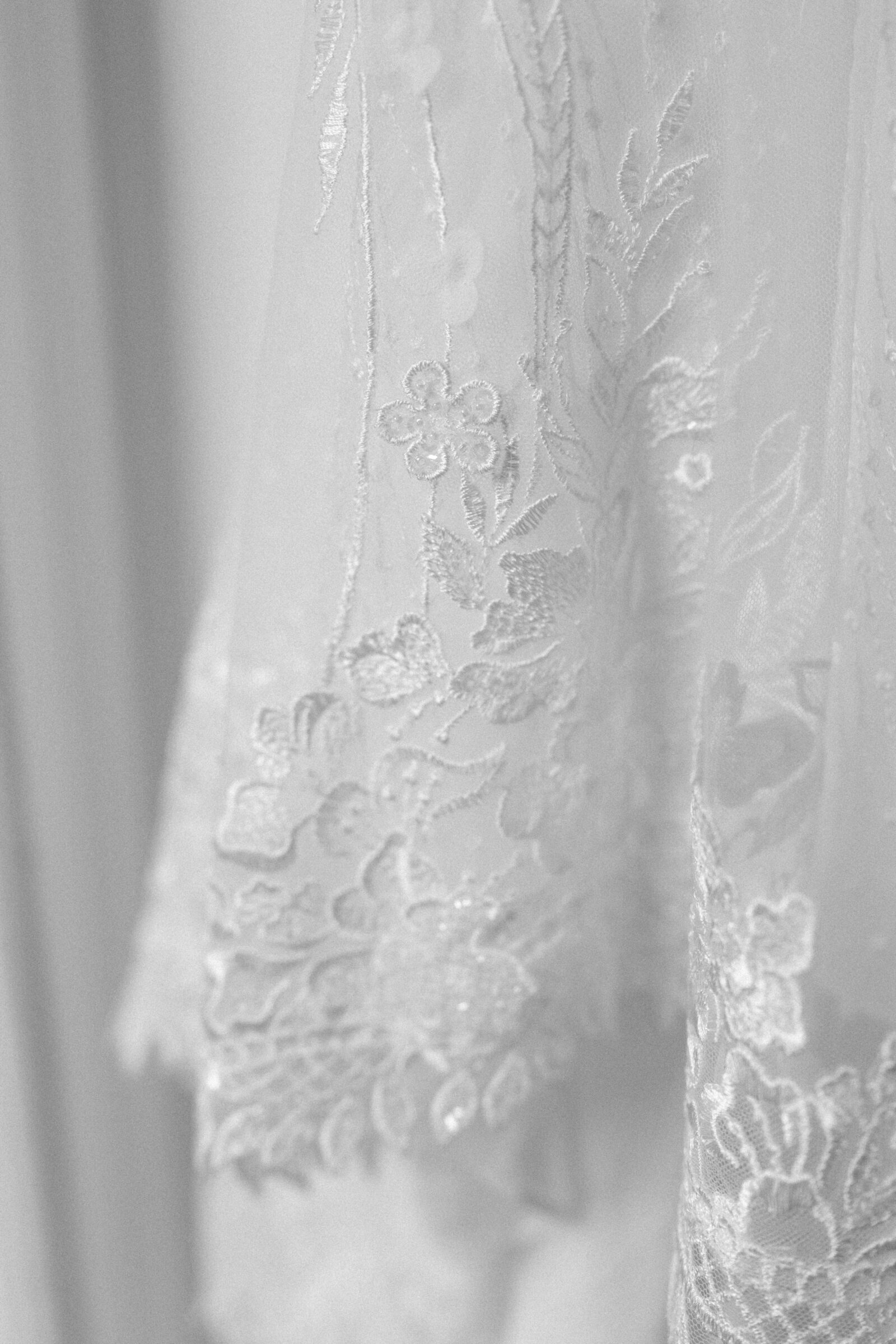 black and white image of delicate lace trim of a bridal gown | captured by Caitlin Wilcox Photography, a film wedding photographer in Richmond, VA