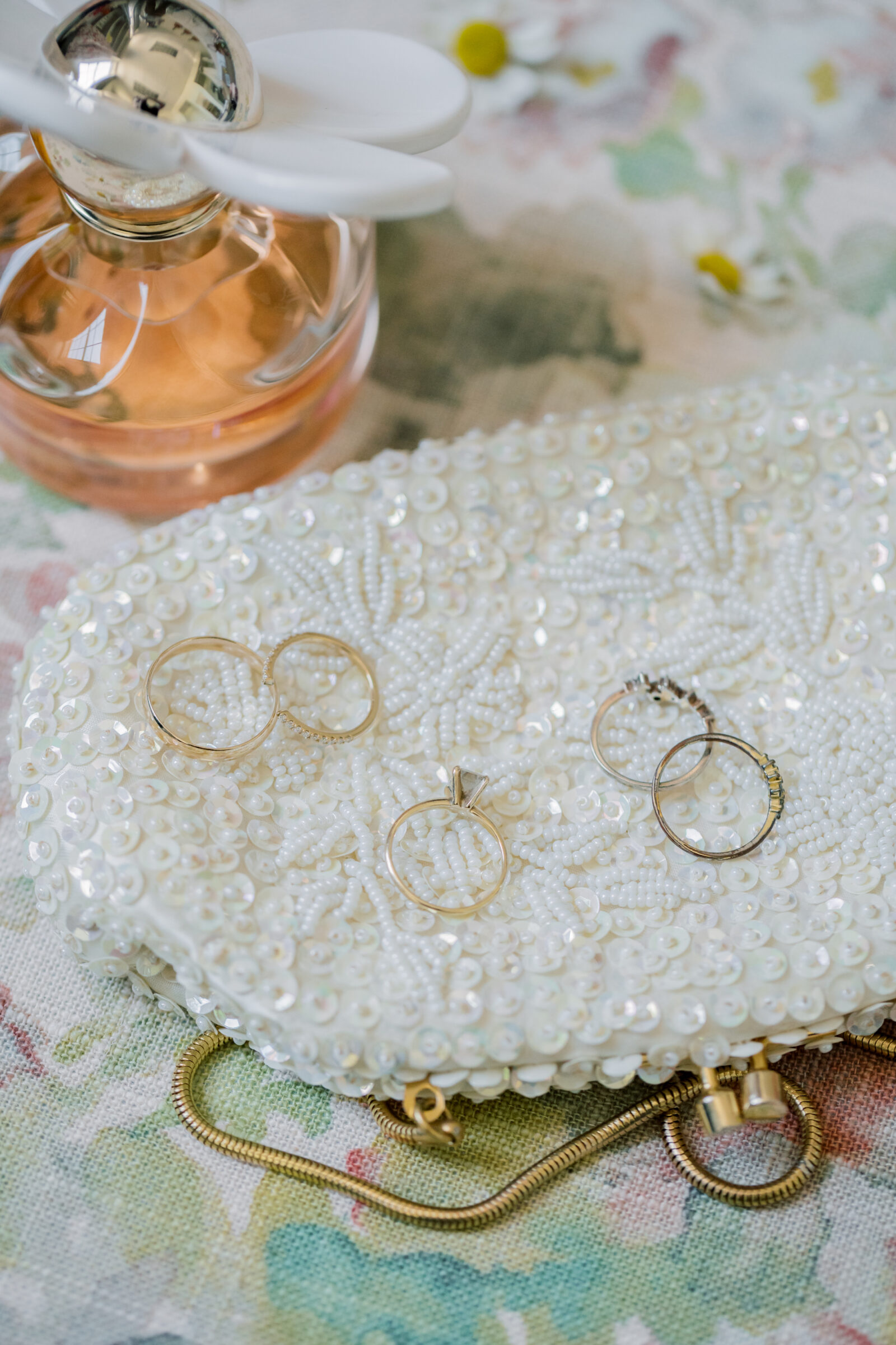 Gold wedding rings and heirloom rings on a pearl inspired purse with Daisy by Marc Jacobs perfume in the background | Three Oaks Manor wedding in Madison Heights, VA