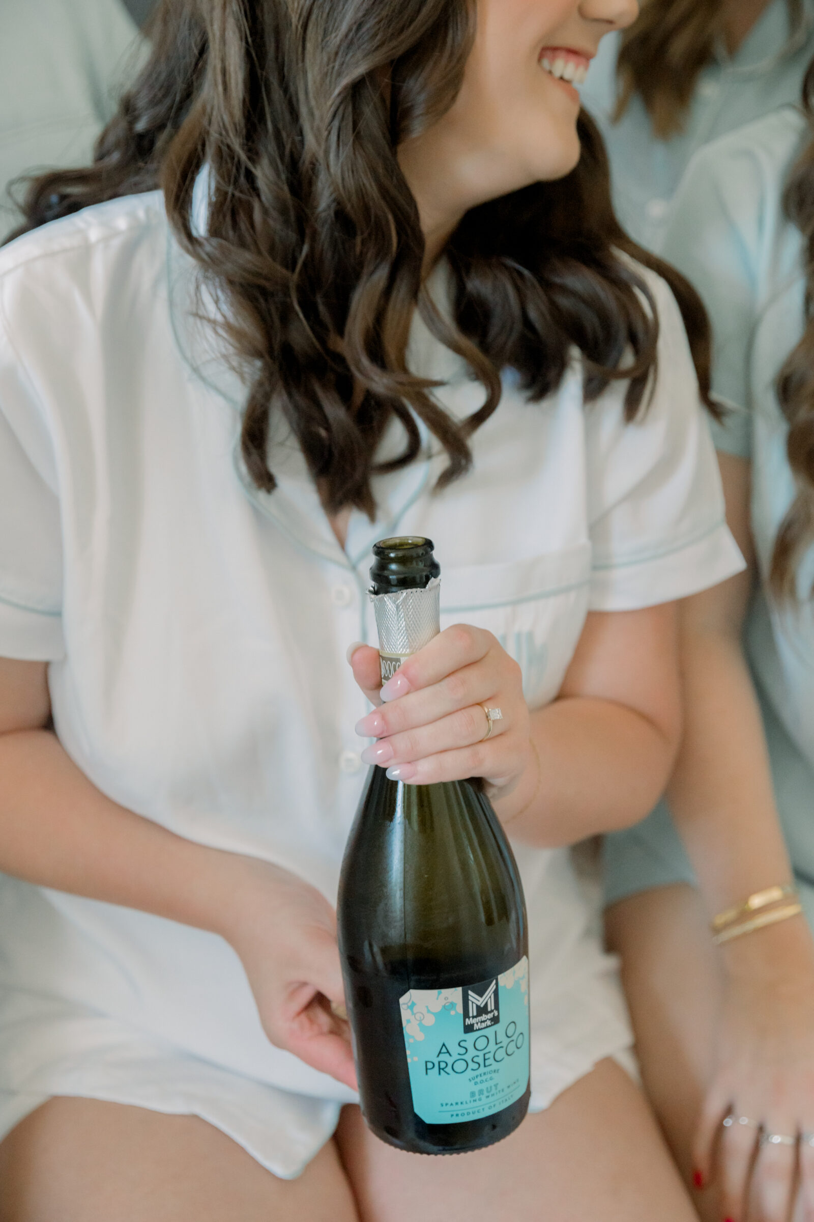 Lynchburg Wedding Photographer | bride in white pajamas holds bottle of Prosecco while getting ready for her wedding