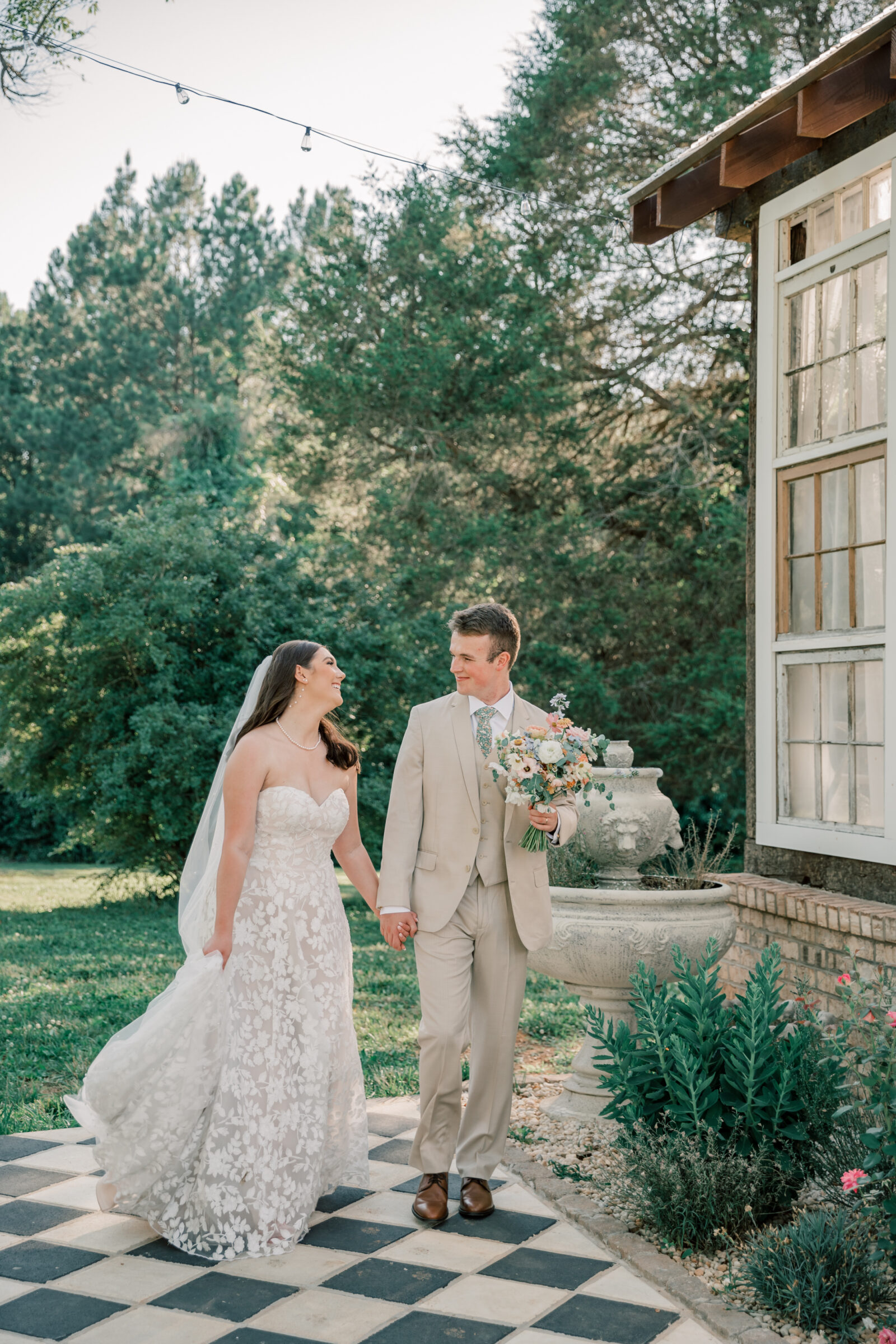 Three Oaks Manor Wedding in Madison Heights, VA | Virginia Wedding Photographer | bride in white floral gown and groom in tan suit hold hands as they walk