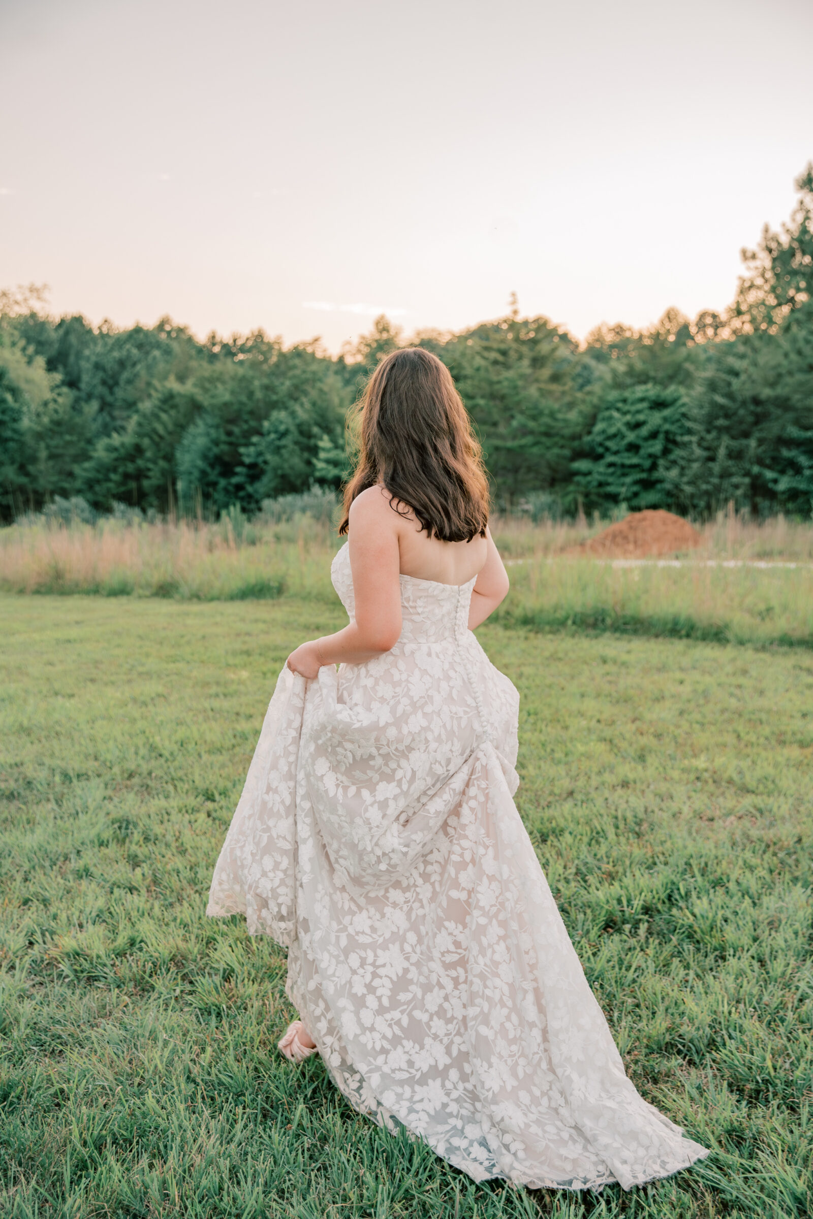 Three Oaks Manor Wedding in Madison Heights, VA | Virginia Wedding Photographer | bride in floral wedding dress walks in the sunset holding her dress