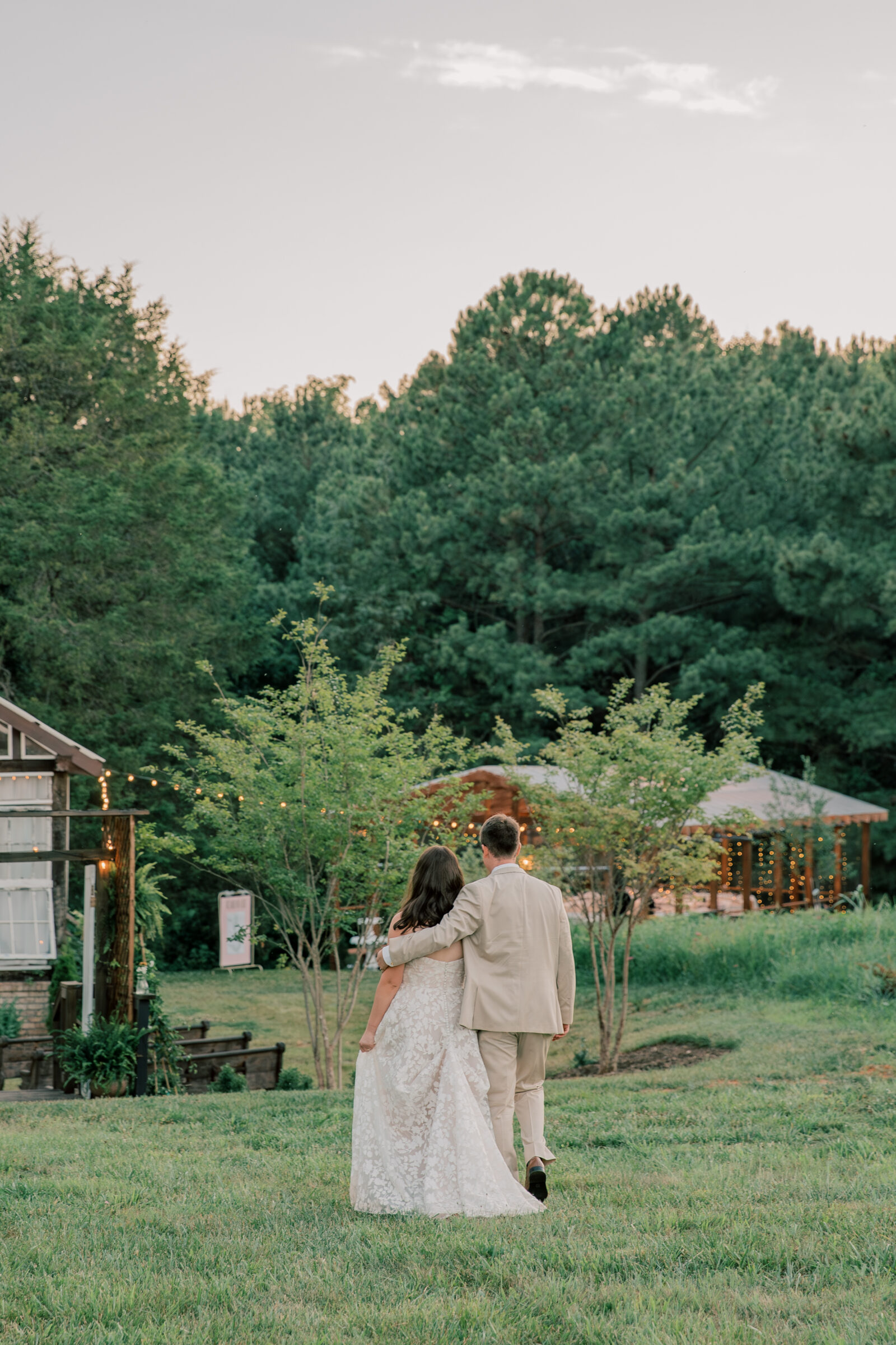 Three Oaks Manor Wedding in Madison Heights, VA | Virginia Wedding Photographer | groom has arm around bride as they walk towards their venue after sunset pictures