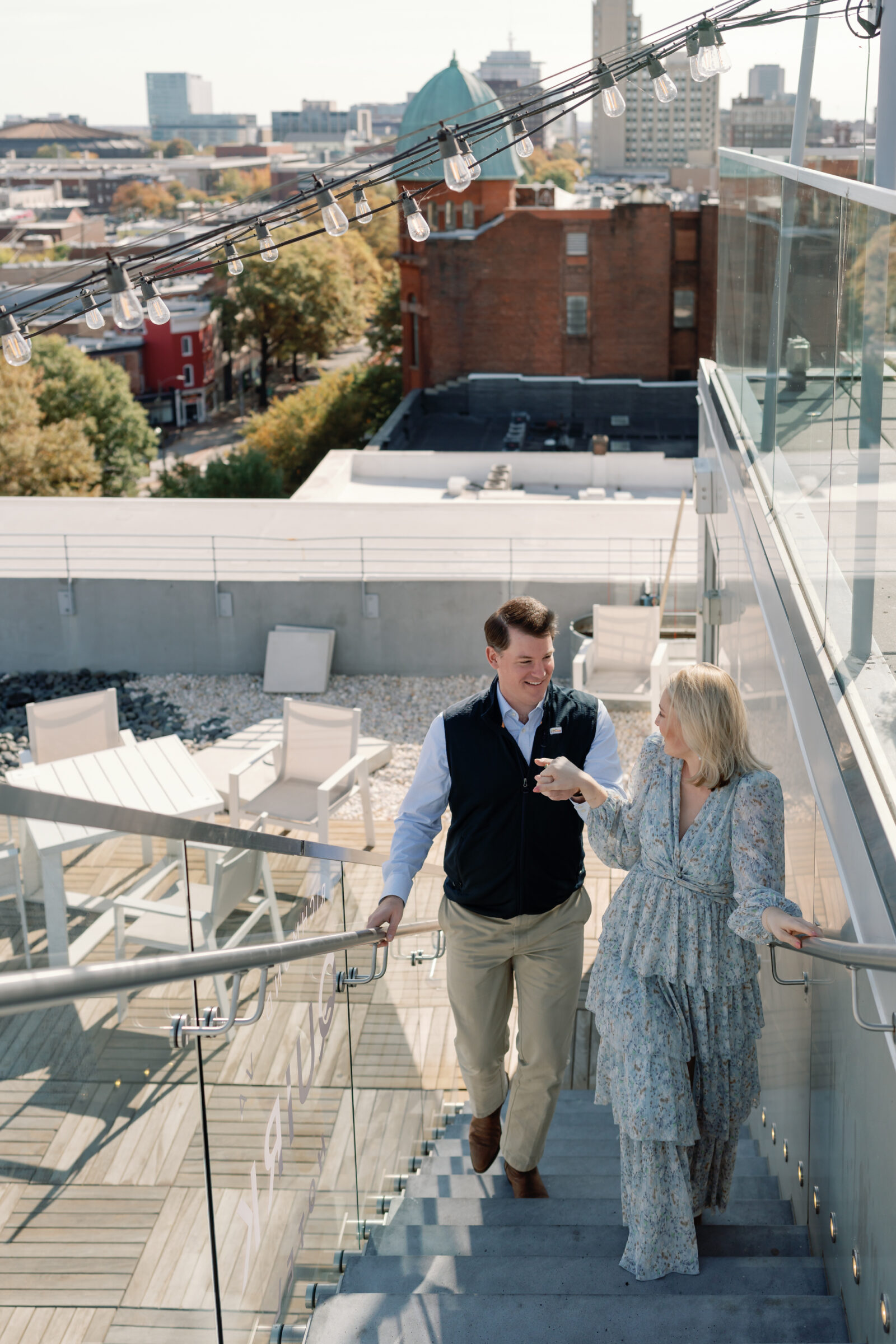 Quirk Hotel RVA Engagement Session in Richmond, VA | Wedding Photographer in Richmond | couple walking up the stairs hand in hand on the rooftop of the Quirk Hotel in Richmond