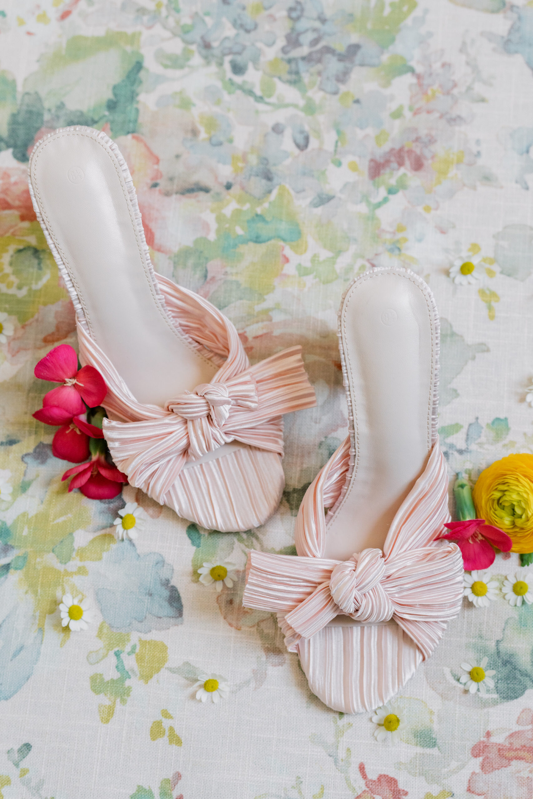 Virginia Wedding Photographer - Bridal Detail Photos | pink wedding shoes with a bow surrounded by colorful florals on a floral backdrop