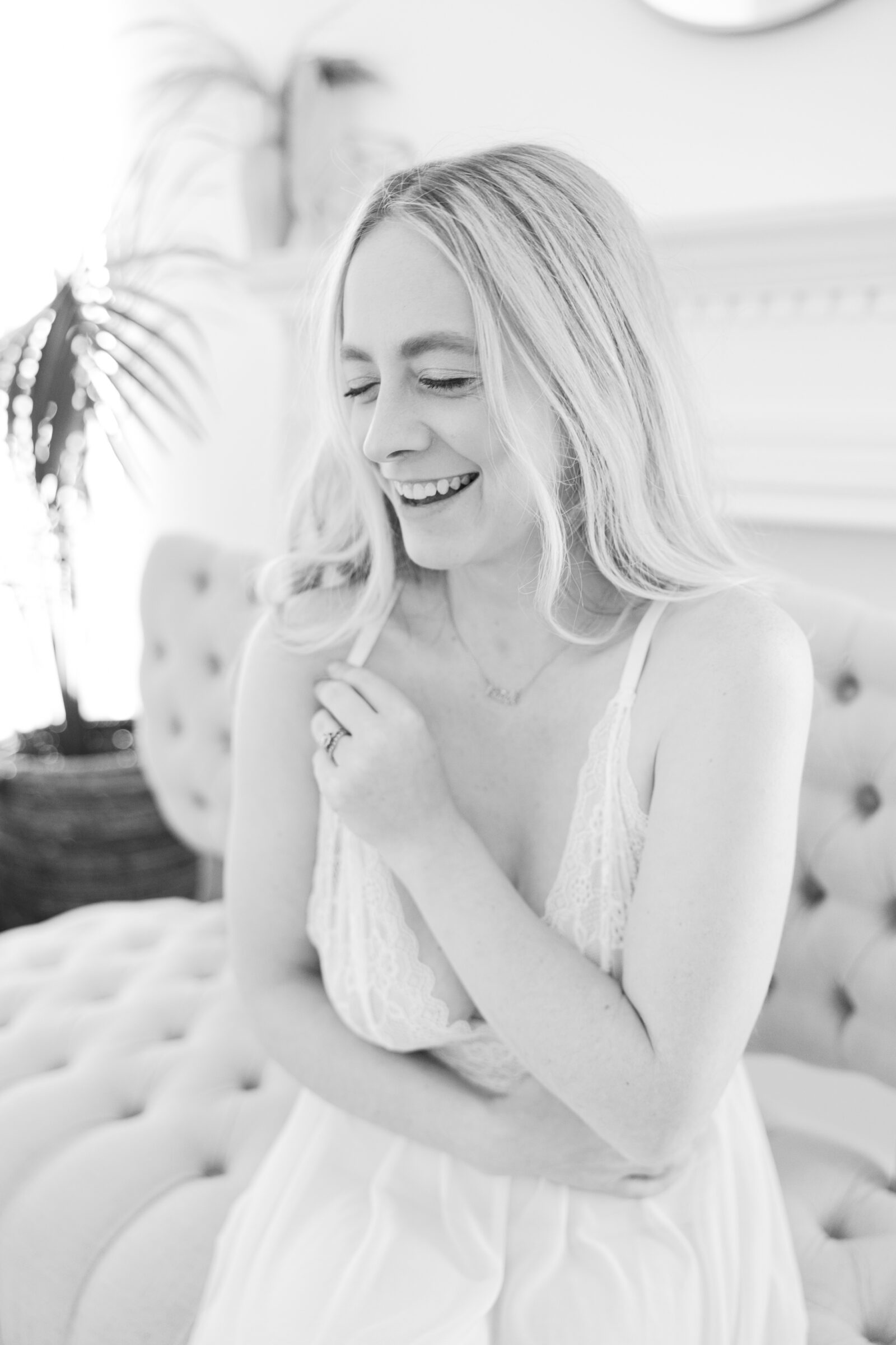Romantic Bridal Boudoir Session in Richmond VA | a black and white image of a girl in white lace lingerie laughing