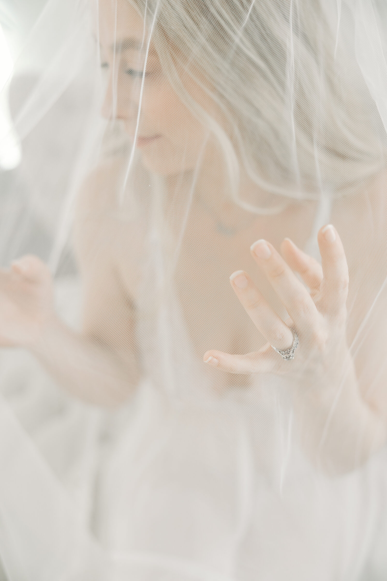 Romantic Bridal Boudoir Session in Richmond VA | closeup image of a girl in white lace lingerie's engagement ring taken through her bridal veil
