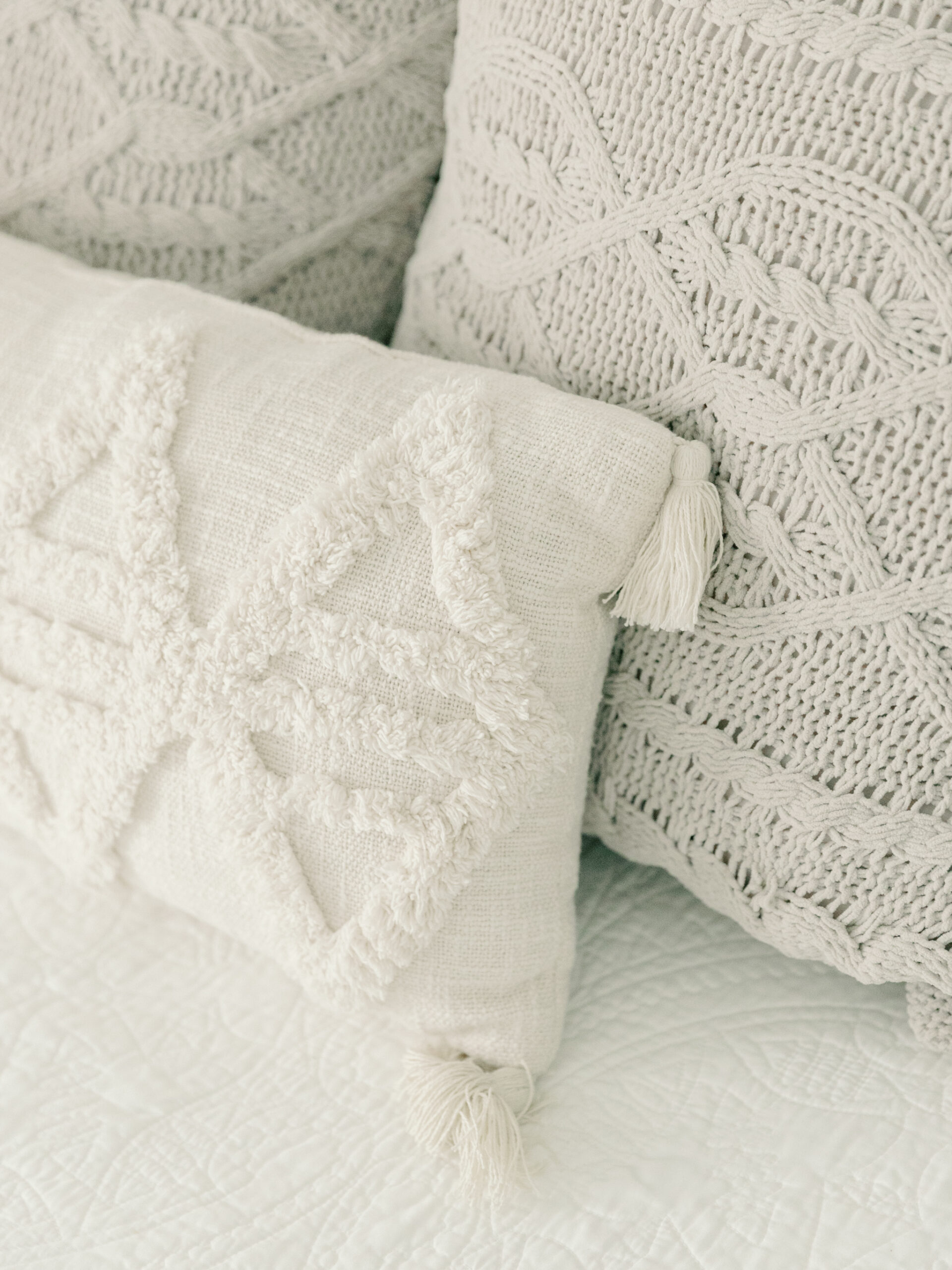 Close-up of cozy, textured pillows in a boudoir photography studio in Ashland, VA near Richmond, featuring neutral, woven designs with tassels. These soft details contribute to the inviting and serene atmosphere of Carbone Studios, offering a comfortable and intimate setting for boudoir sessions.