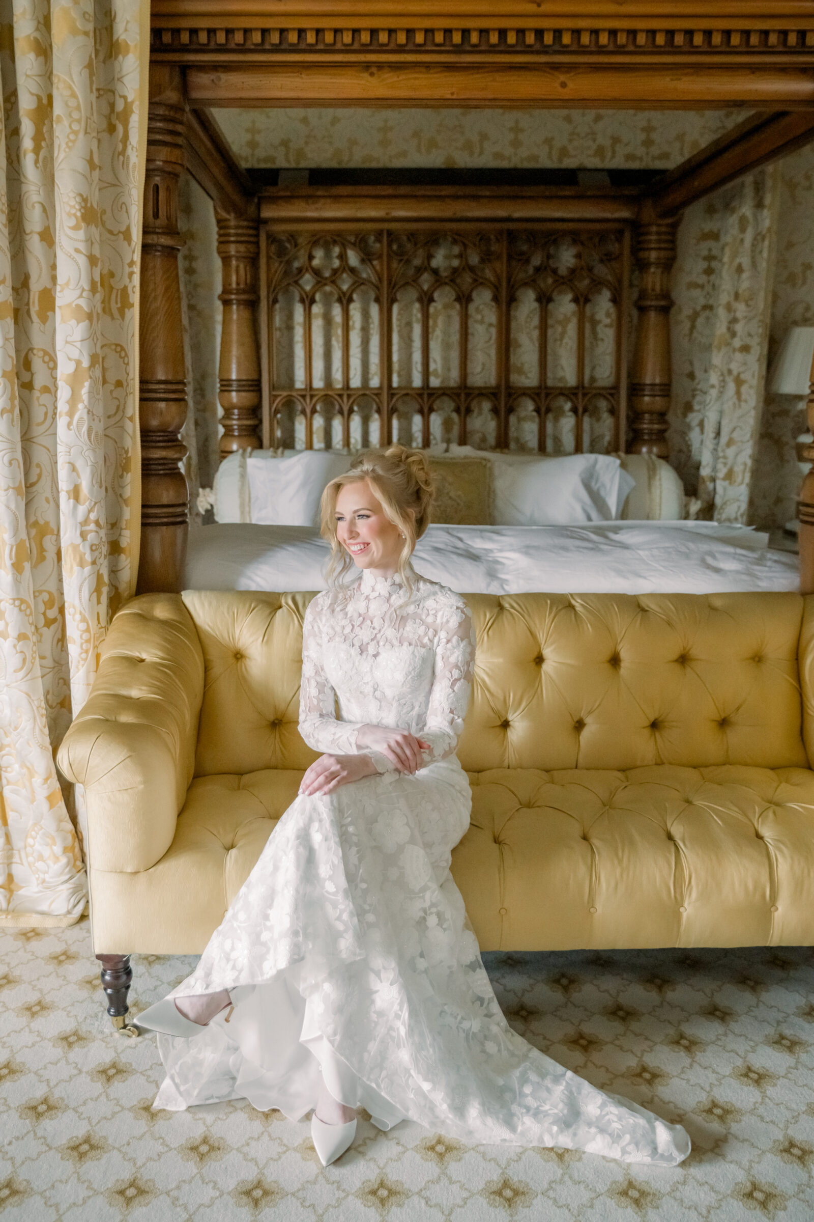 A beautiful bride in a lace wedding dress sitting on a vintage yellow sofa in the bridal suite at Dover Hall Richmond VA, smiling softly as natural light streams through the window.