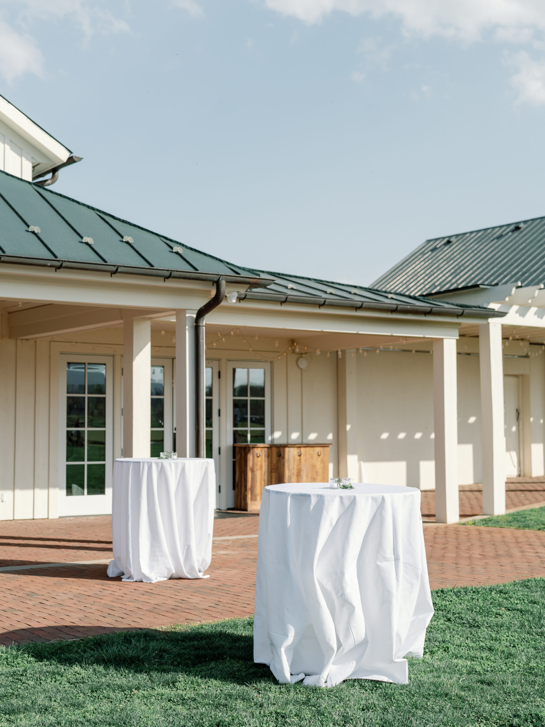 Cocktail tables with white linens set up outside the King Family Vineyards event space, creating a relaxed atmosphere for guests to enjoy the scenic surroundings.