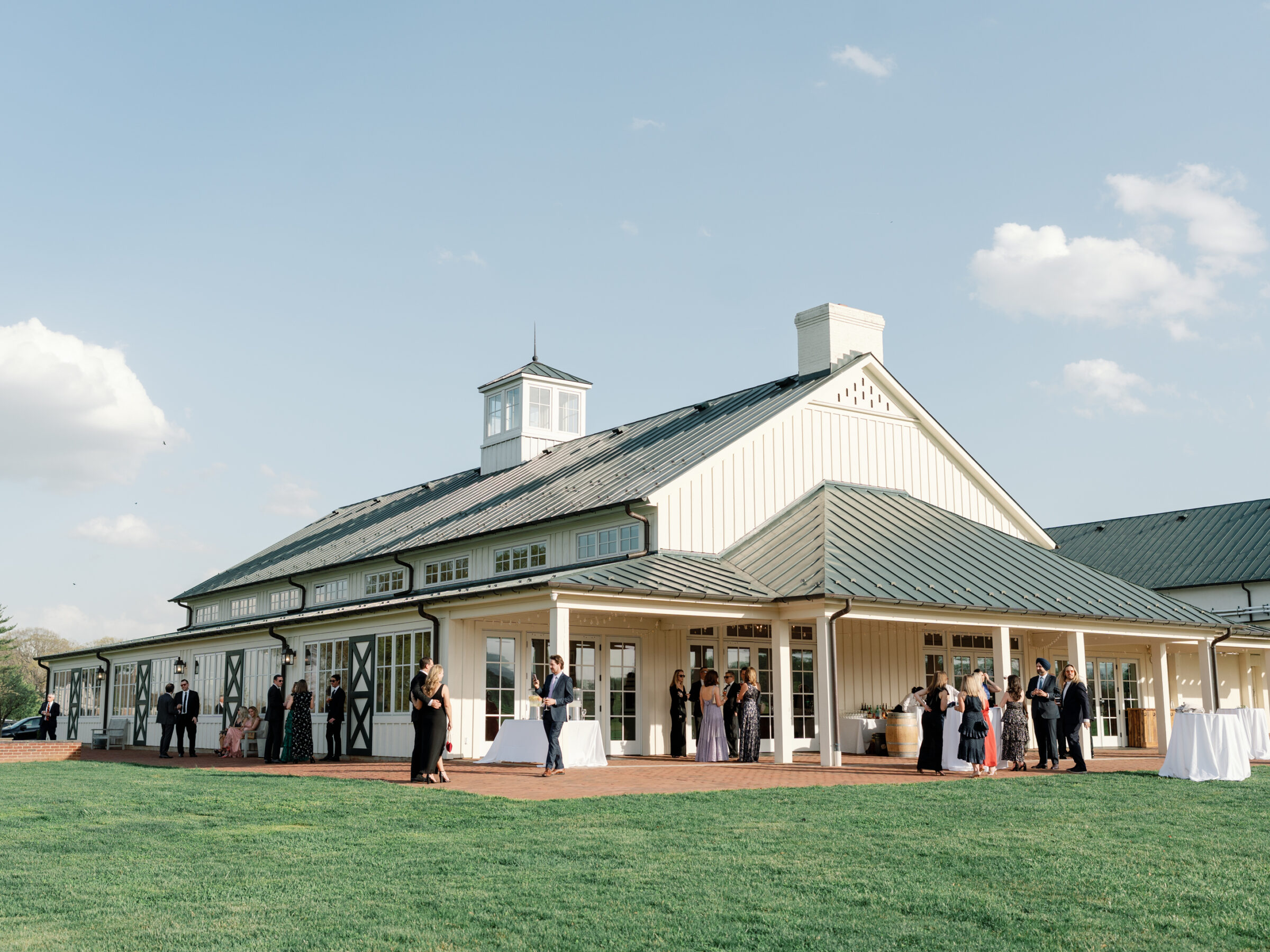 Exterior of the King Family Vineyards event space during a wedding reception, with guests mingling and enjoying the beautiful outdoor setting.