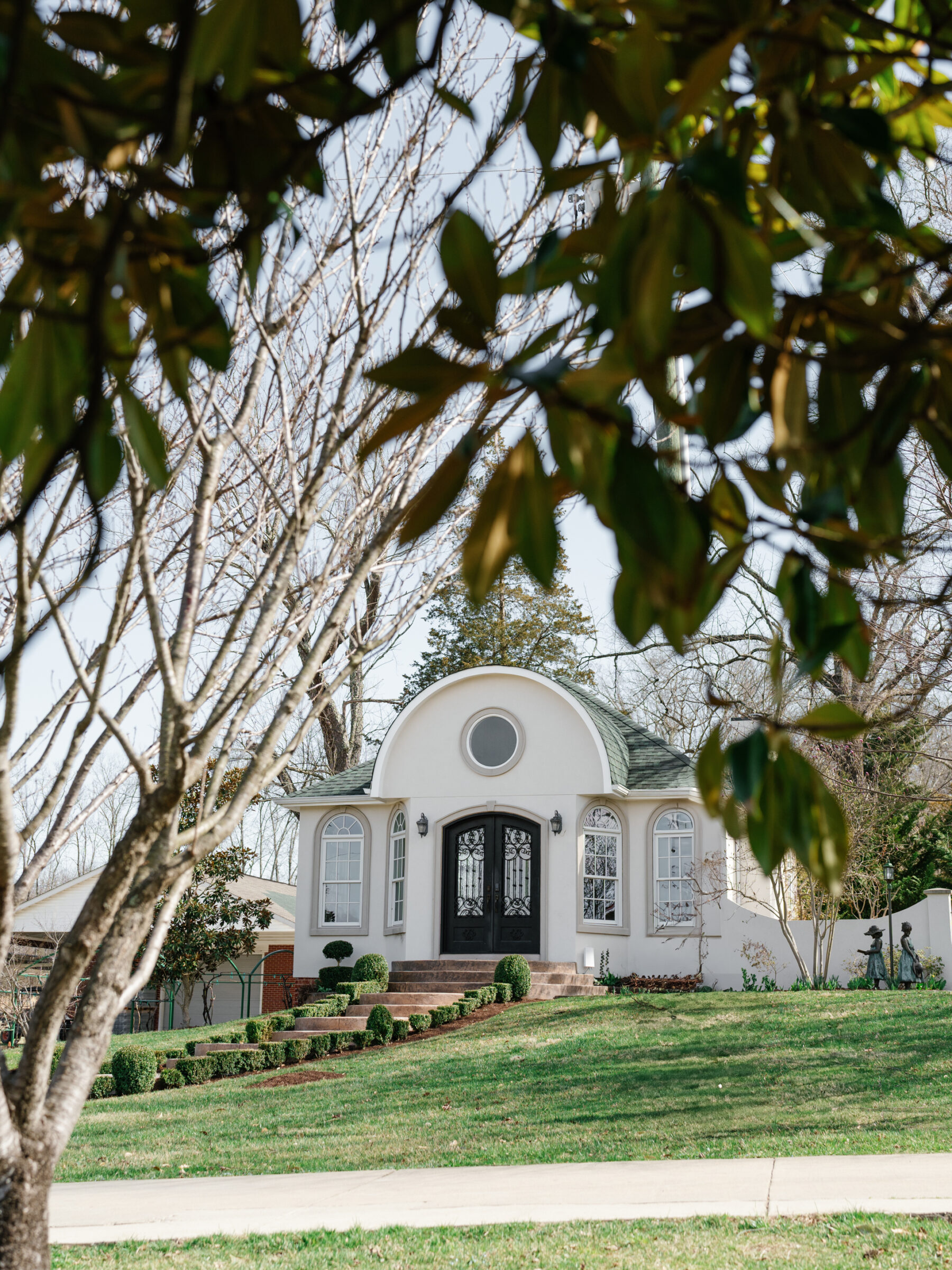 Exterior of the Morais Vineyards wedding chapel, framed by trees with a well-manicured lawn and stone steps leading up to the grand entrance.