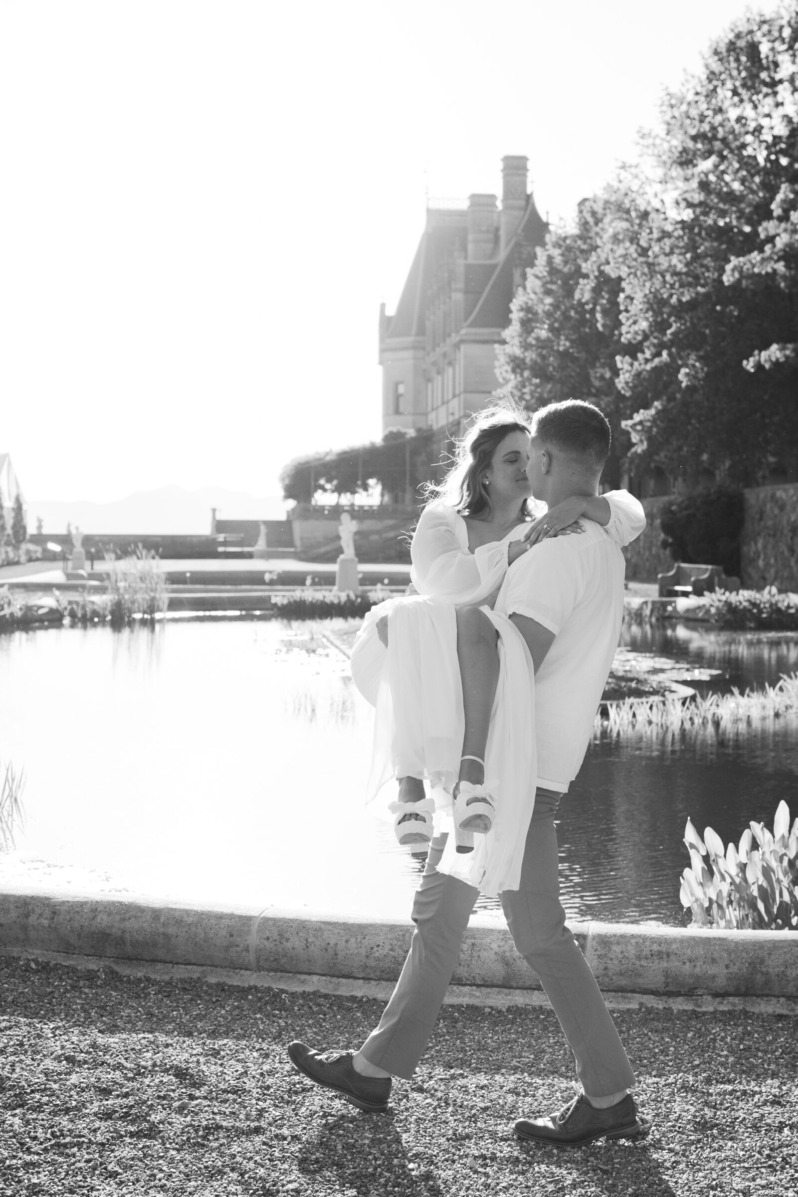 Engagement Photos at the Biltmore Estate | black and white image of guy carrying girl in the Biltmore Italian Gardens