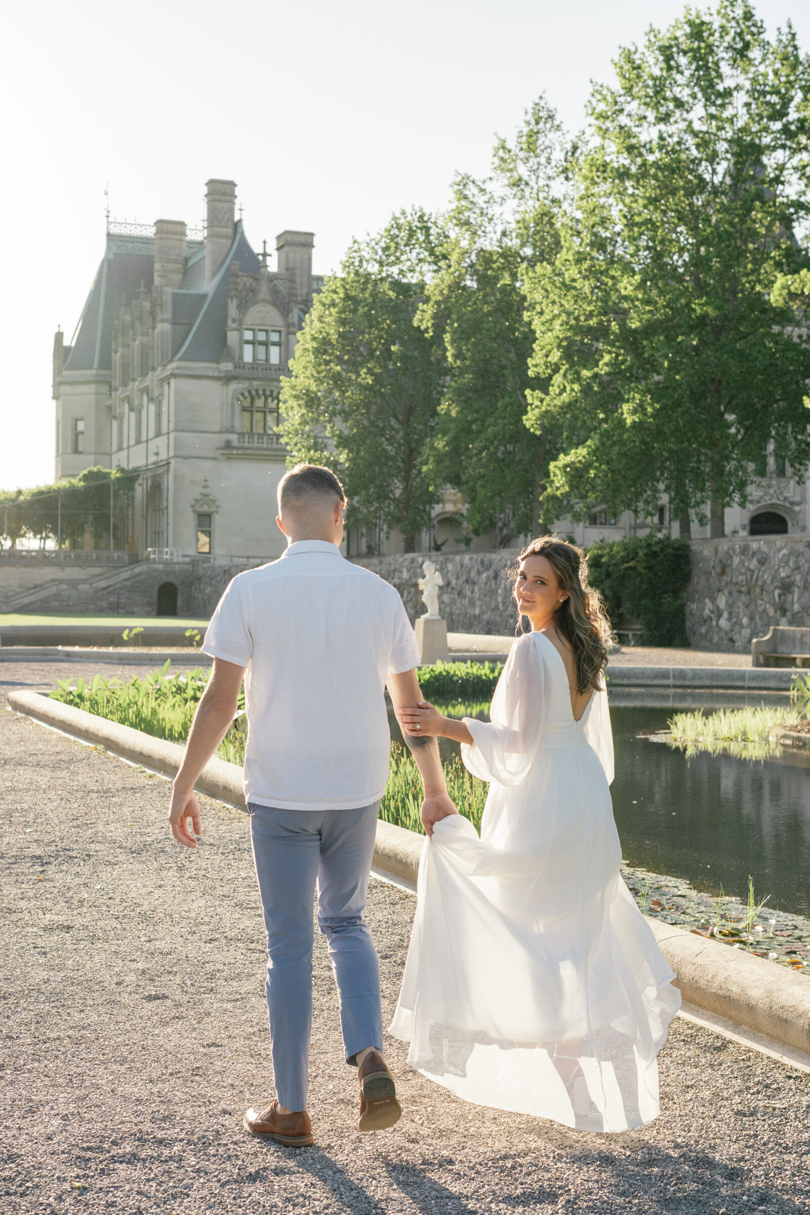 Engagement Photos at the Biltmore Estate | couple walking away from camera, girl looks behind her into the camera