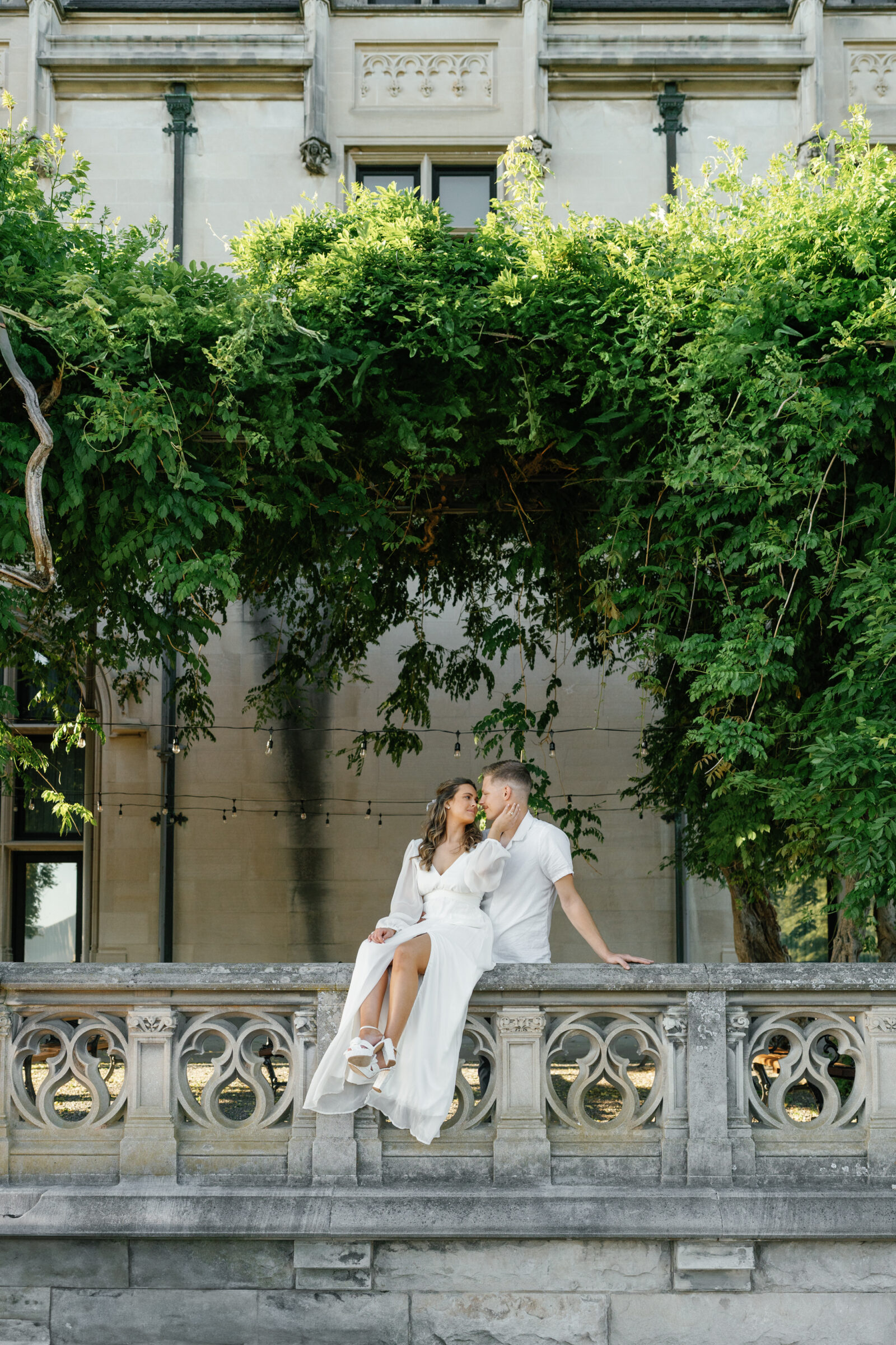Engagement Photos at the Biltmore Estate | couple sits on terrace railing
