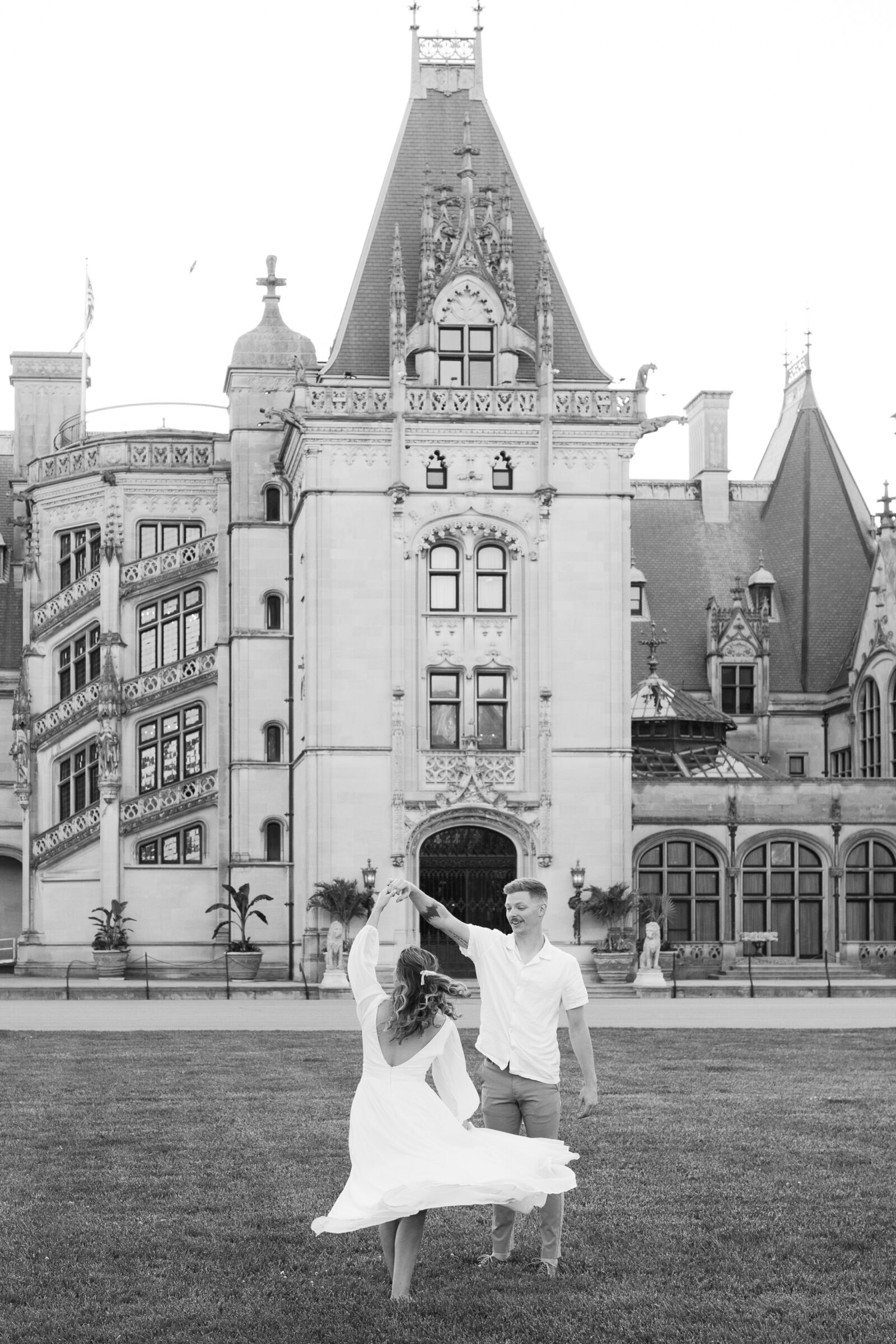 Engagement Photos at the Biltmore Estate House | black and white image of couple spinning on front lawn of the Biltmore
