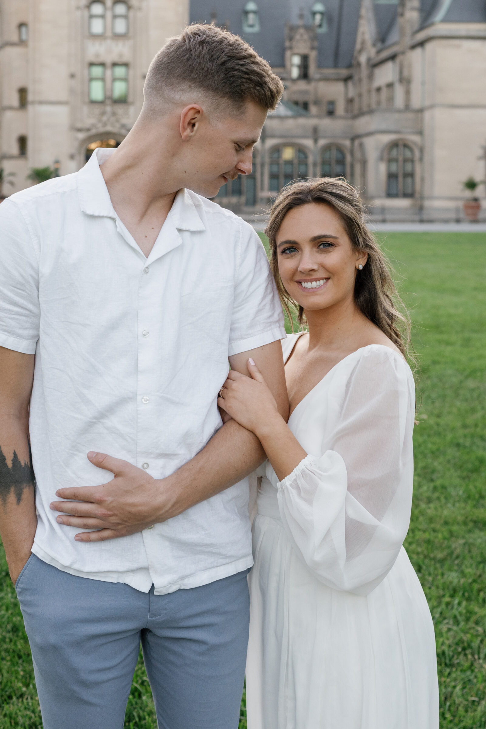 Engagement Photos at the Biltmore Estate House | girl looks at camera while hugging guy's arm. he looks at her