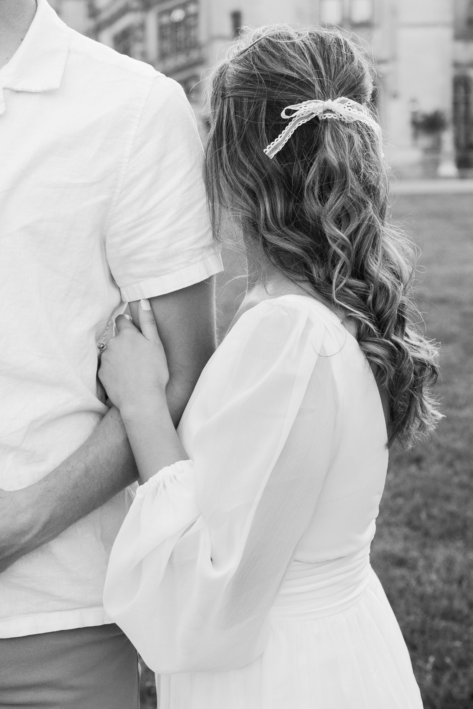 Engagement Photos at the Biltmore Estate | girl hugs guy's arm, showing off the white bow in her hair