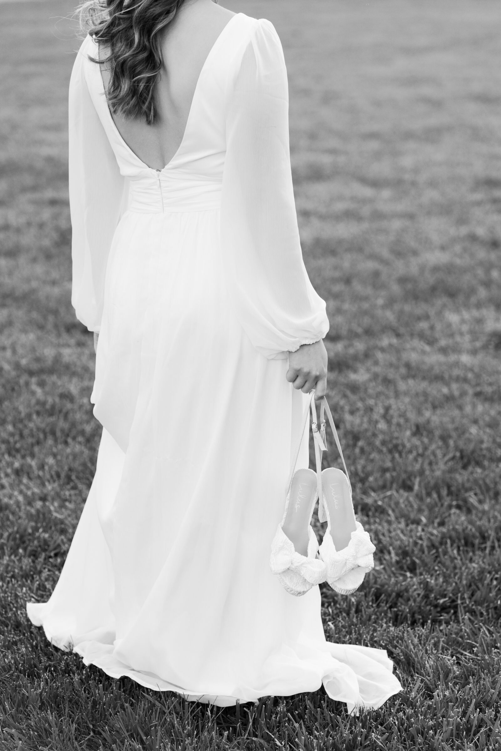 Engagement Photos at the Biltmore Estate House | girl in white dress holds shoes on Biltmore front lawn