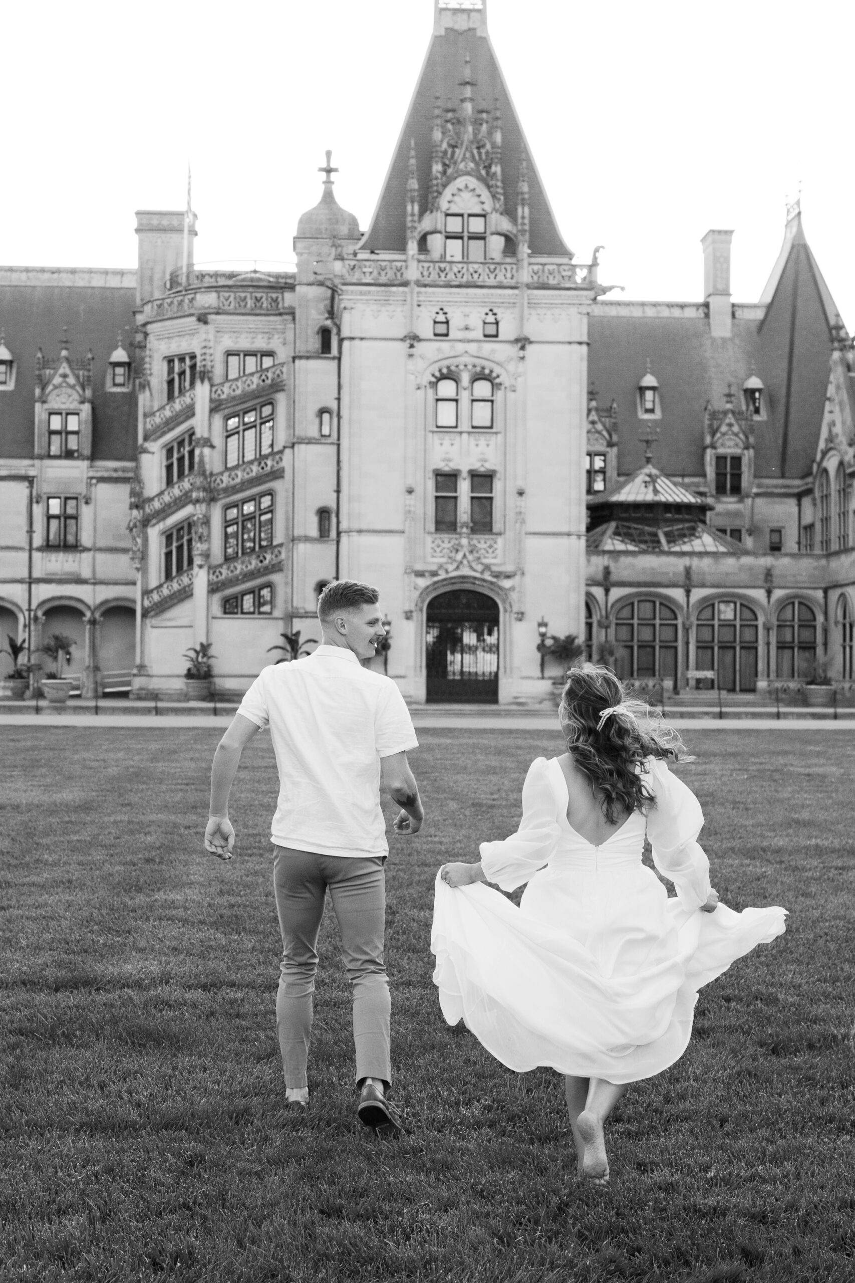 Engagement Photos at the Biltmore Estate House | couple run towards Biltmore House