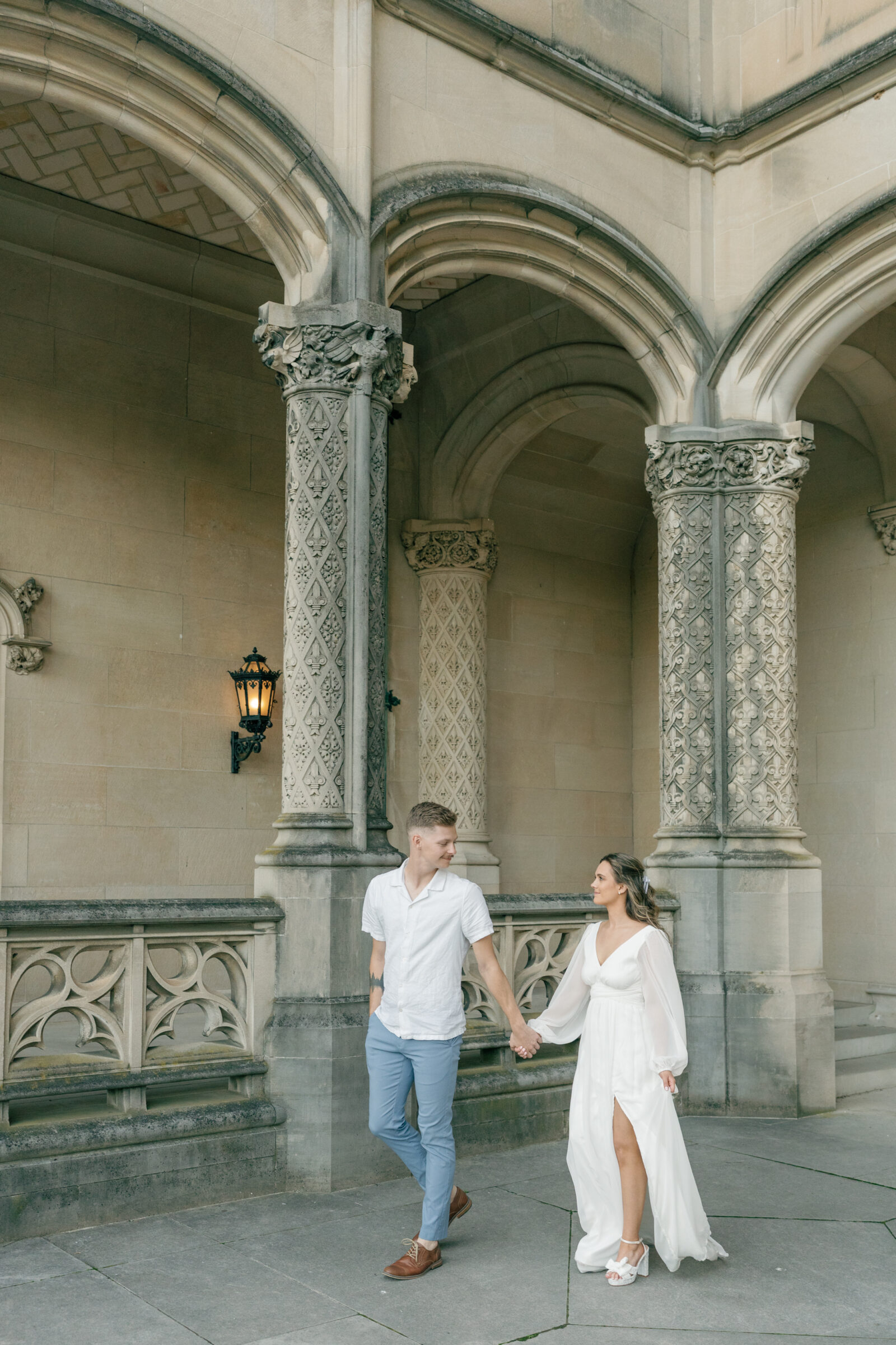 Couple walk hand in hand in front of Biltmore House