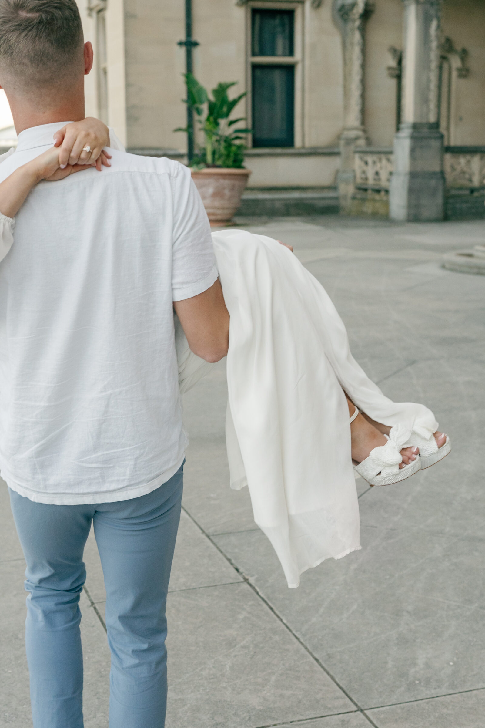 Closeup of girl's shoes as she's carried in front of Biltmore house