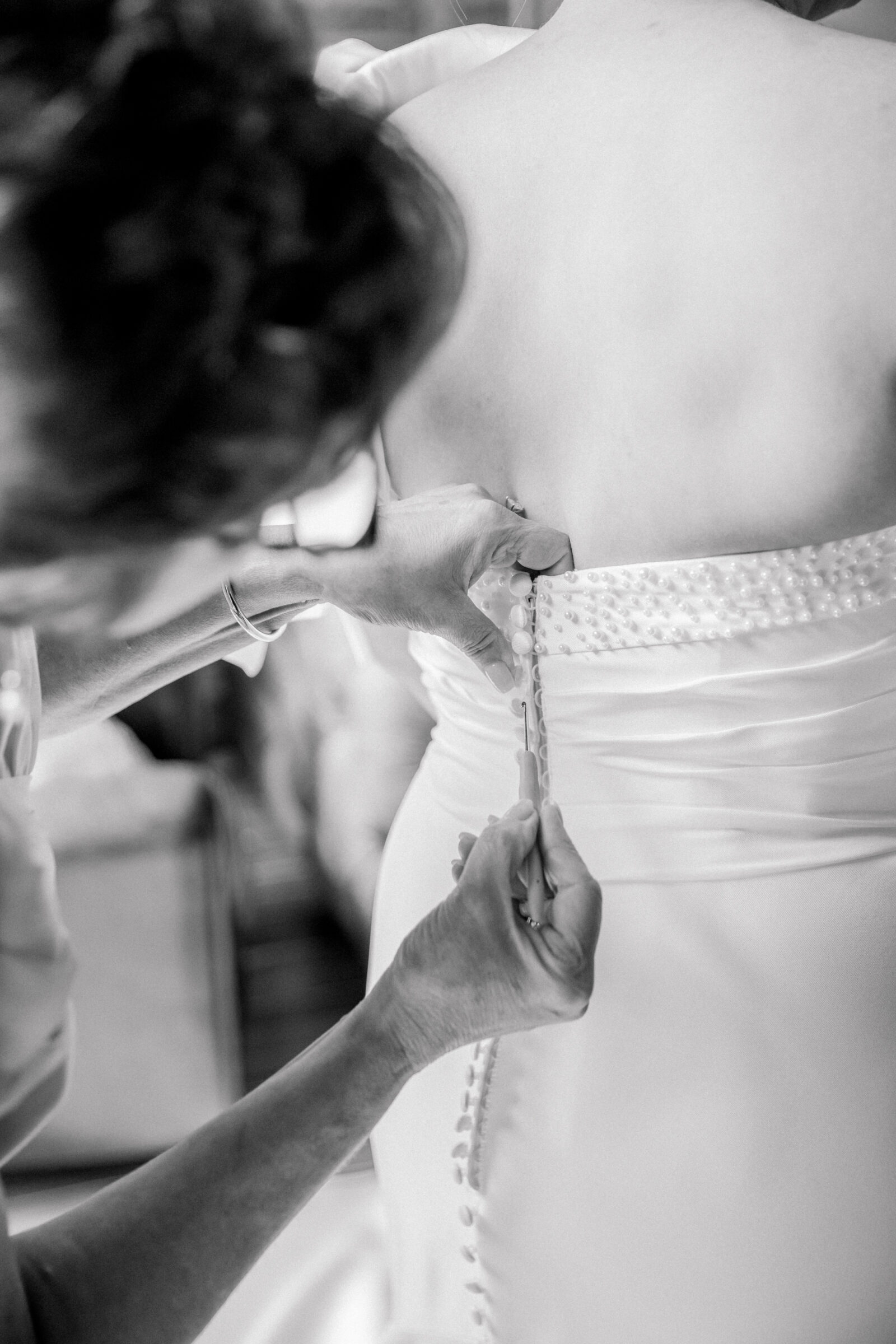 Southwest VA Wedding Photographer | black and white image of bride getting buttoned into wedding dress