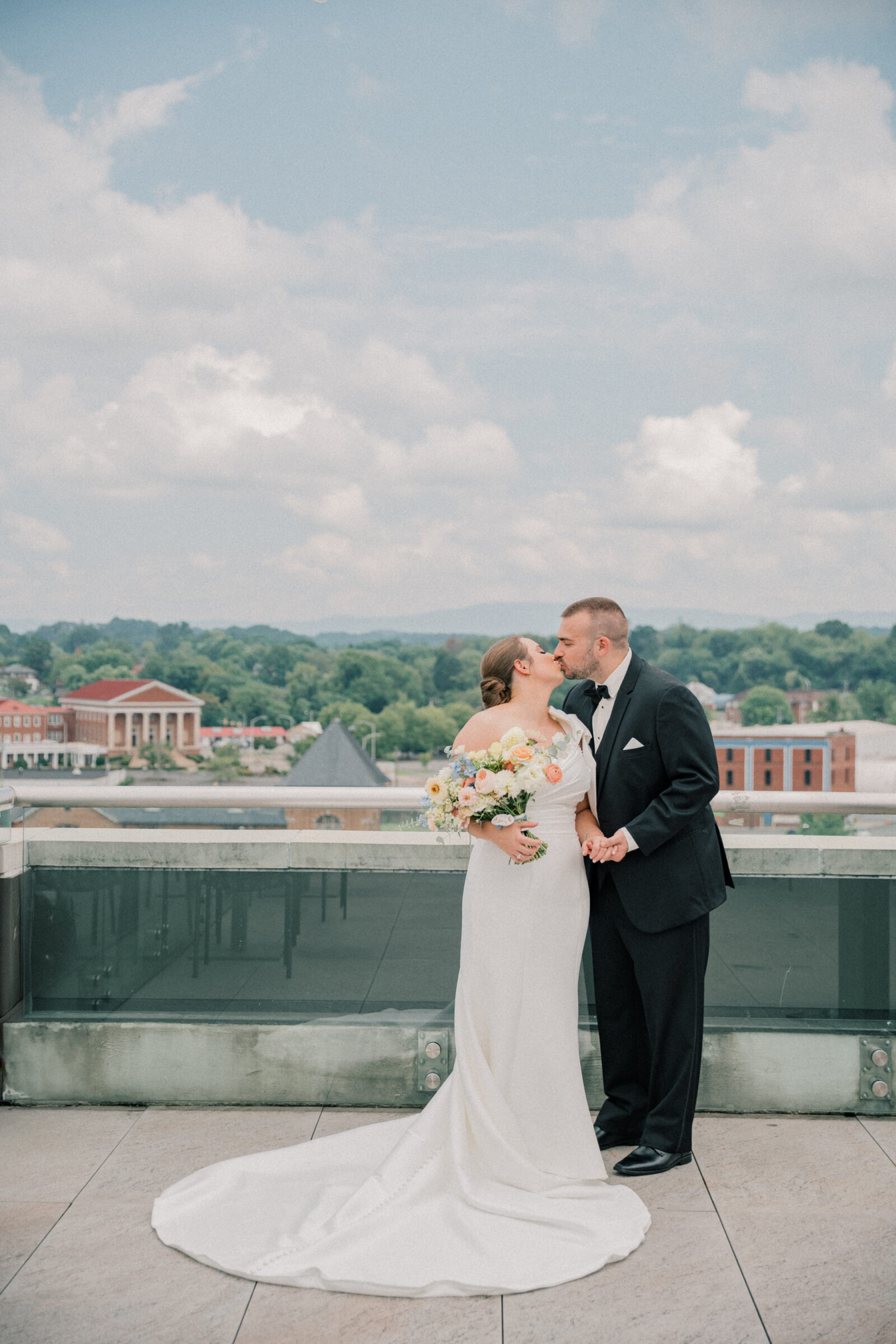 Bristol Hotel Wedding | bride and groom share a kiss on the rooftop of the Bristol Hotel with the city skyline behind them