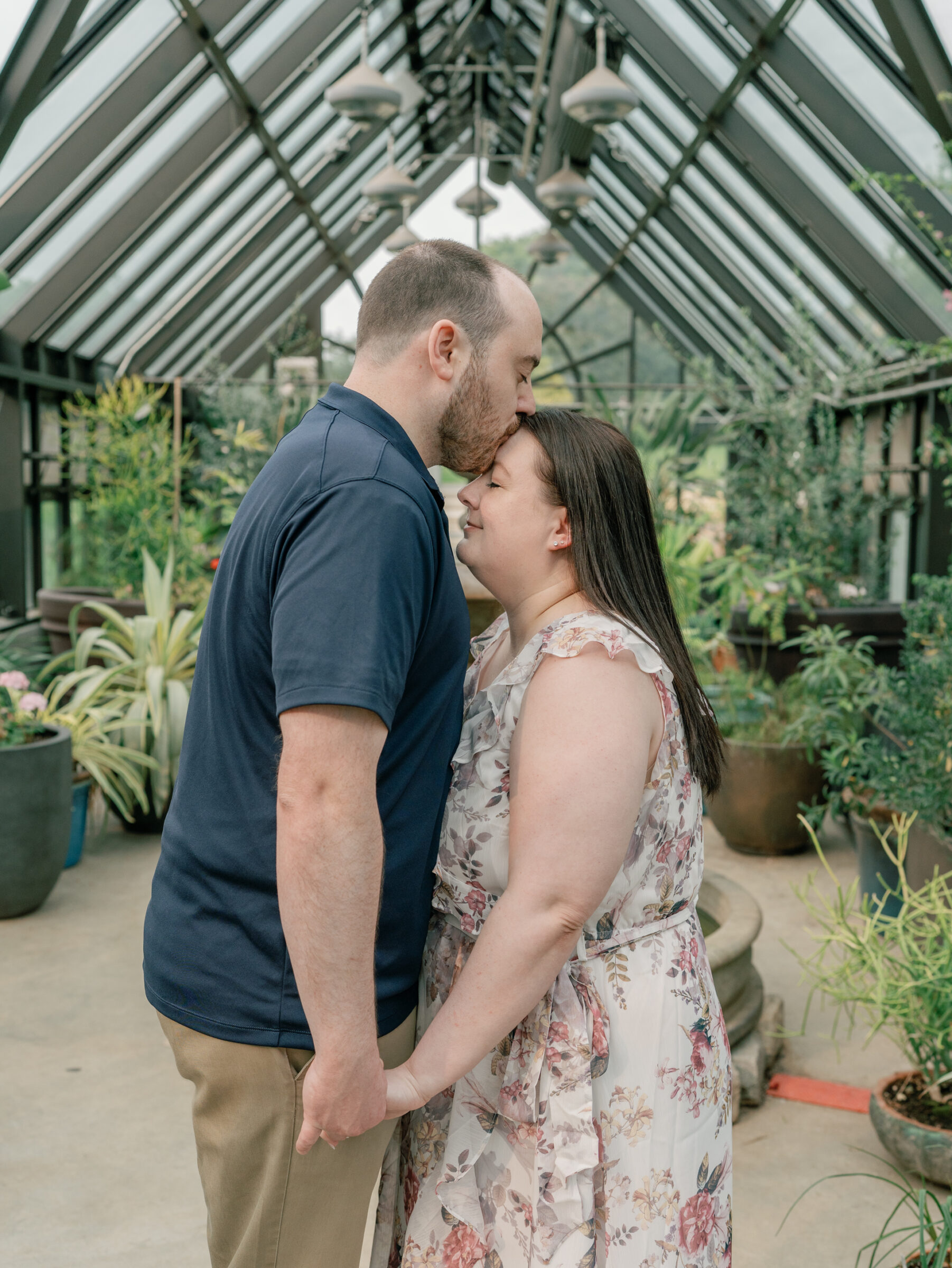 Meadowlark Botanical Gardens Engagement Session | guy in blue polo kisses his bride-to-be on the forehead in a Northern VA botanical garden