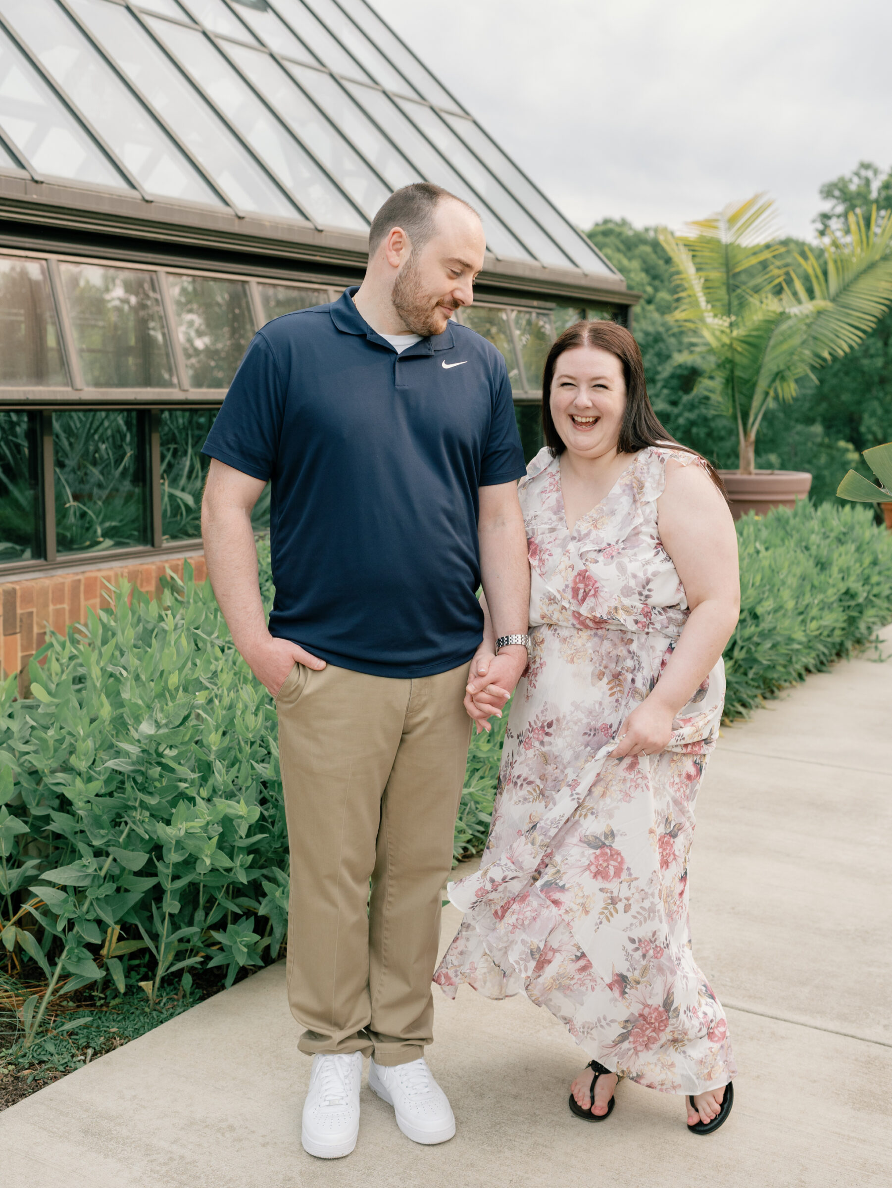 Meadowlark Botanical Gardens Engagement Session | girl in floral dress laughs towards camera while holding hands with her fiance and twirling her dress