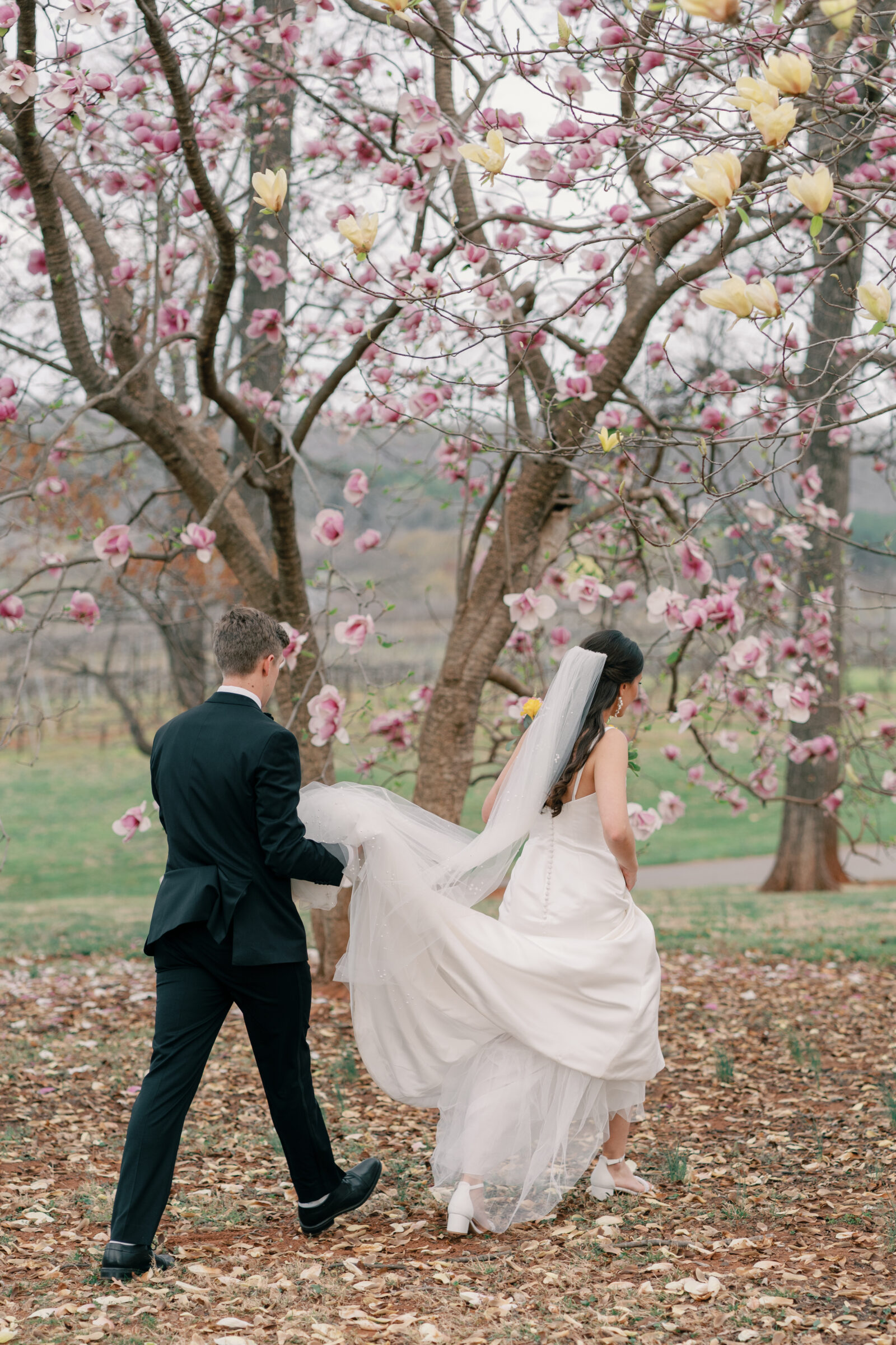 Trump Winery Grand Hall in Charlottesville, VA | groom holds his bride's train as she walks ahead of hiim