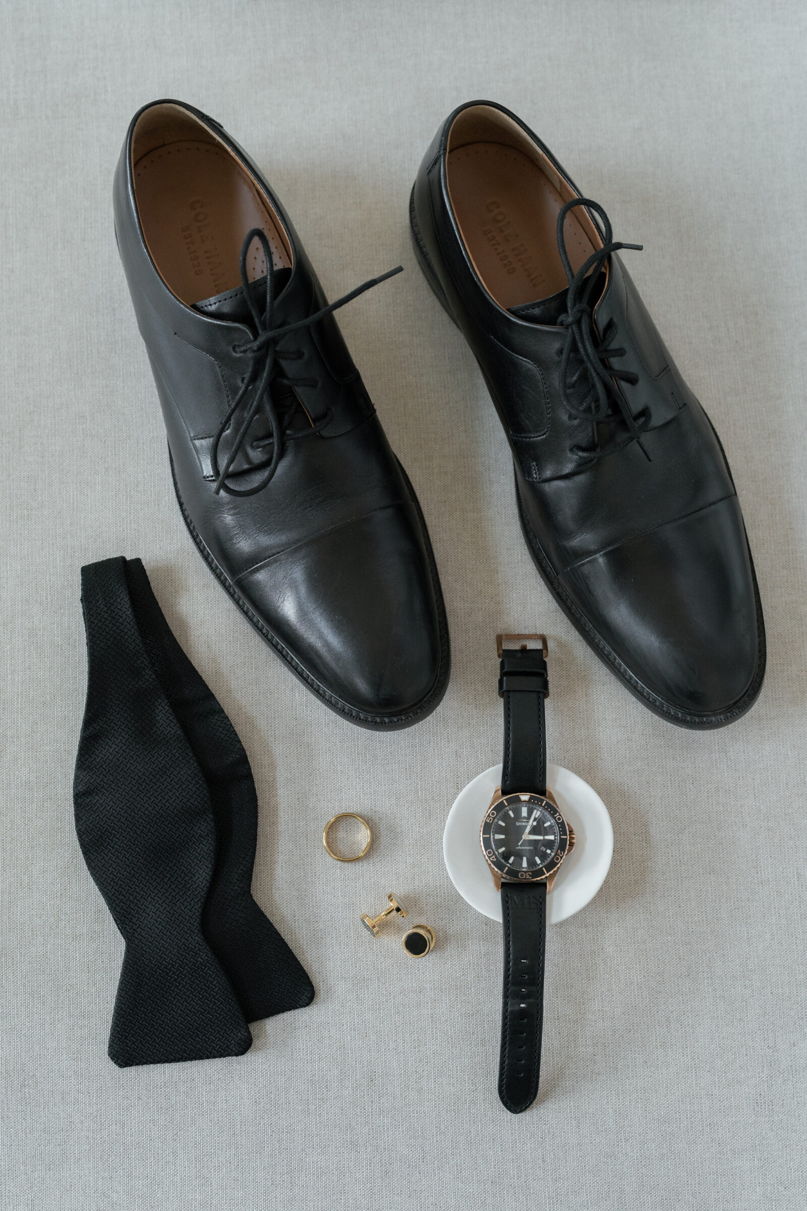 Charlottesville VA Wedding Photographer | groom detail flat lay photo with black dress shoes, watch, bowtie, cufflinks, watch, and gold wedding band.