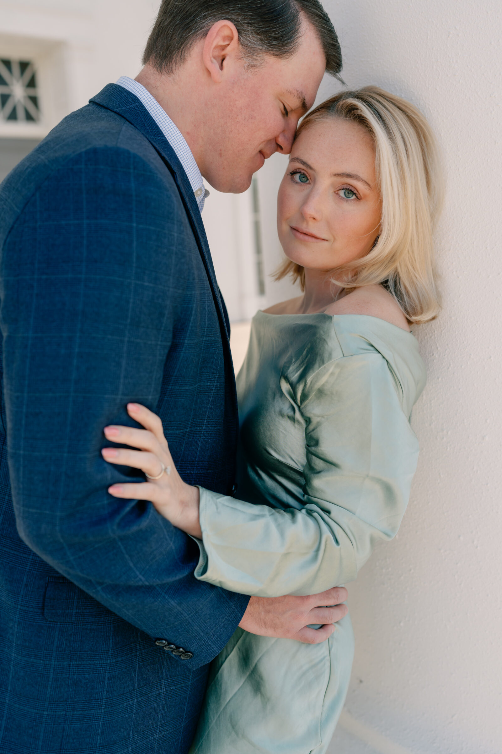 Richmond Engagement Session | girl in green satin dress looks at camera while groom nuzzles into her lovingly | Virginia Capitol Building in Richmond VA