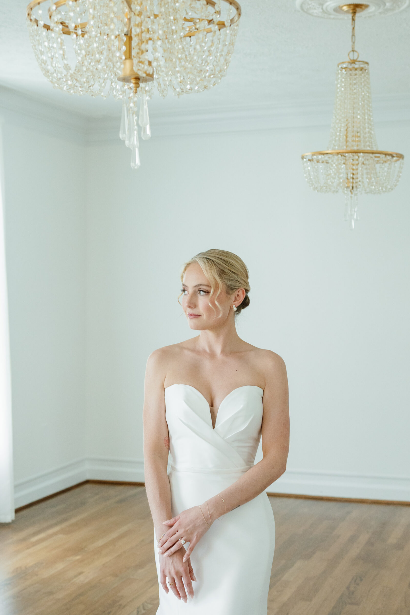 Elegant bridal portrait inside Northfield Estate in Cumberland, VA, featuring a bride in a classic strapless gown beneath vintage crystal chandeliers—refined and romantic bridal suite moments near Richmond.