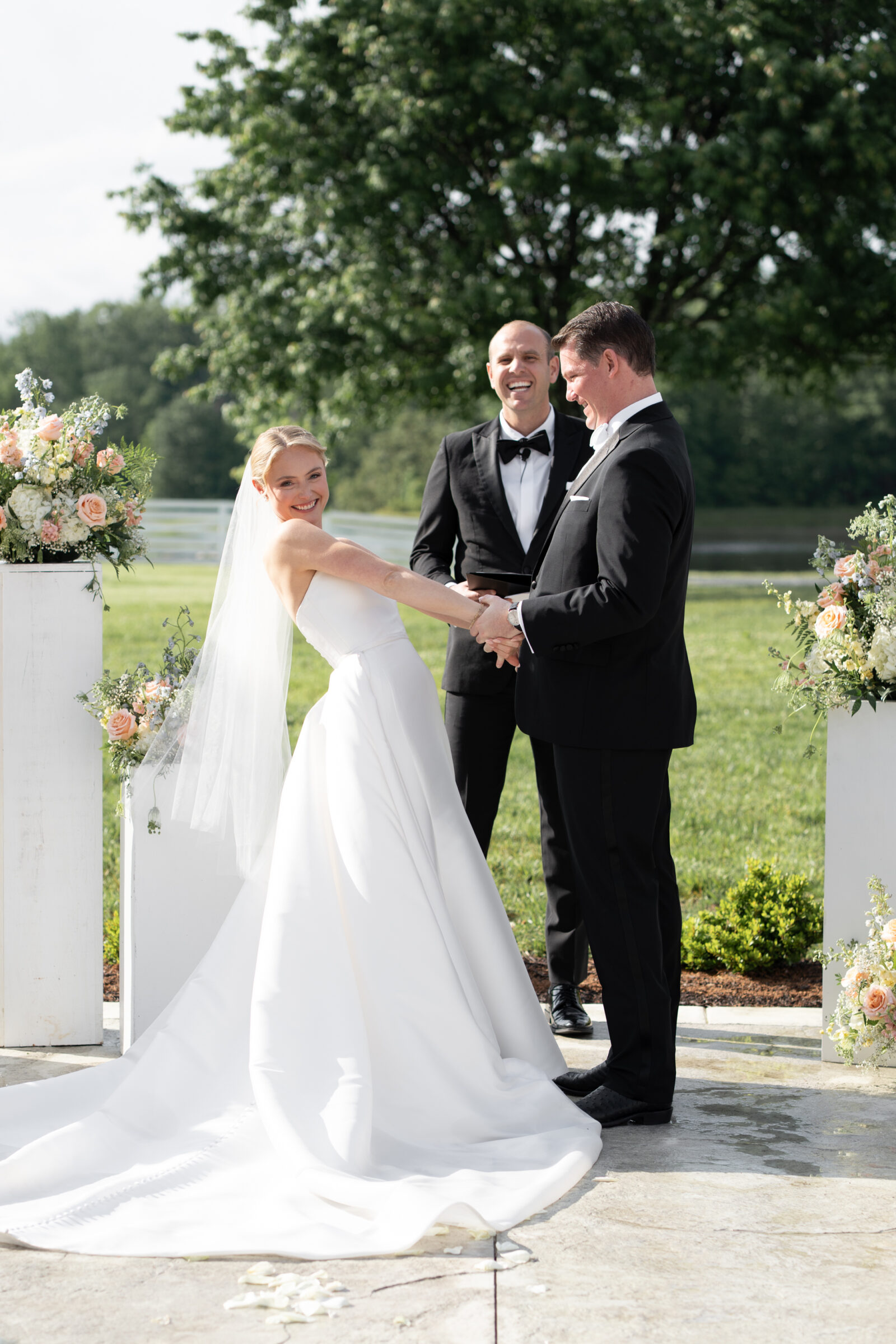 Joyful bride and groom exchanging vows during an outdoor ceremony at Northfield Estate in Cumberland, VA, framed by soft blush floral arrangements and Virginia countryside views—an elegant wedding moment captured just outside Richmond.