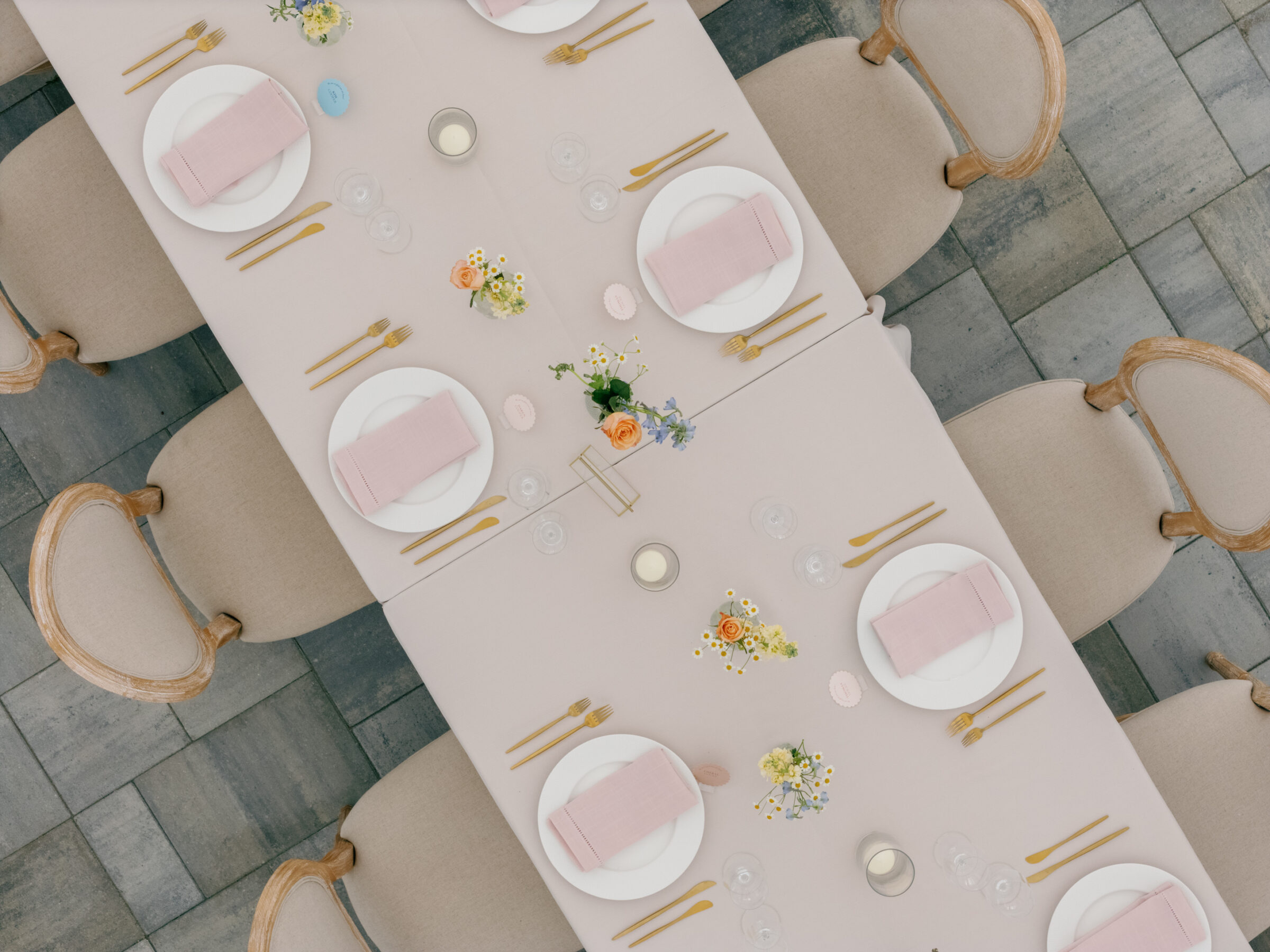 Elegant pastel tablescape at Northfield Estate in Cumberland, VA, featuring blush linens, gold flatware, soft floral centerpieces, and neutral upholstered chairs—perfect for a romantic tented wedding reception near Richmond.