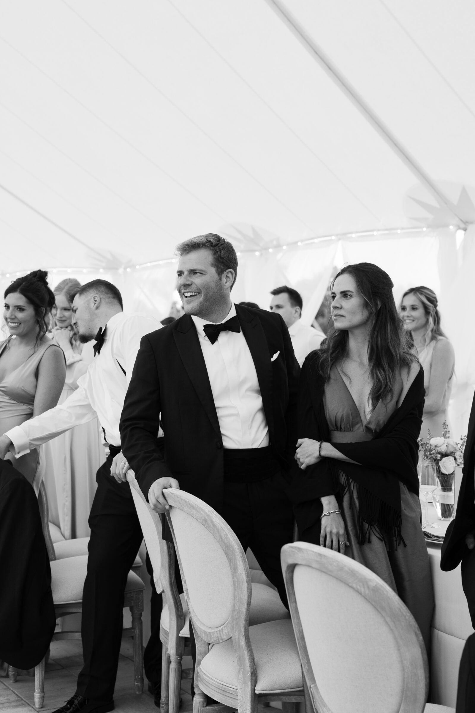 Black and white candid of wedding guests smiling and standing during the reception at Northfield Estate in Cumberland, VA—capturing joyful moments under the elegant sailcloth tent near Richmond.