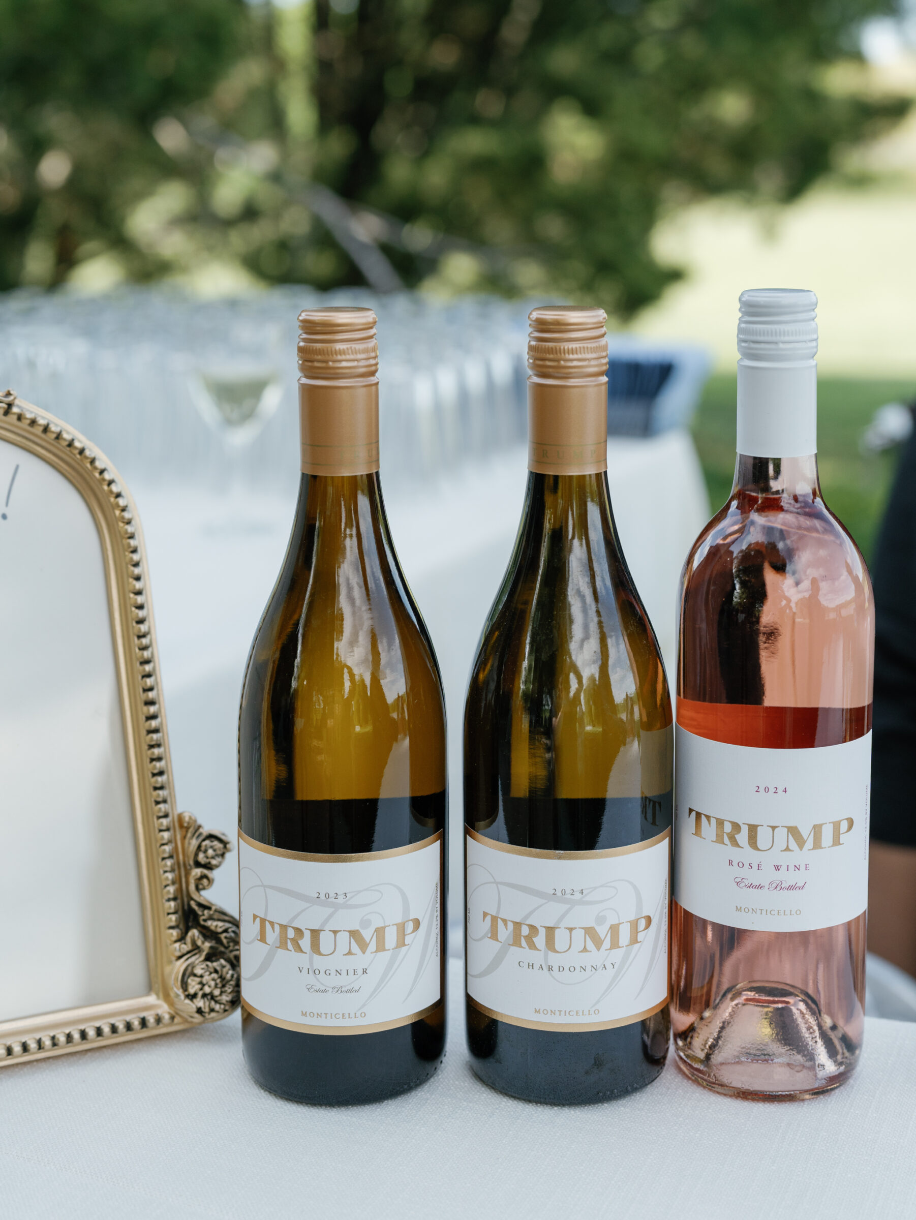Three bottles of Trump Chardonnay, Viognier, and Rosé elegantly displayed on a white-linen table at a Trump Winery Wedding in Charlottesville