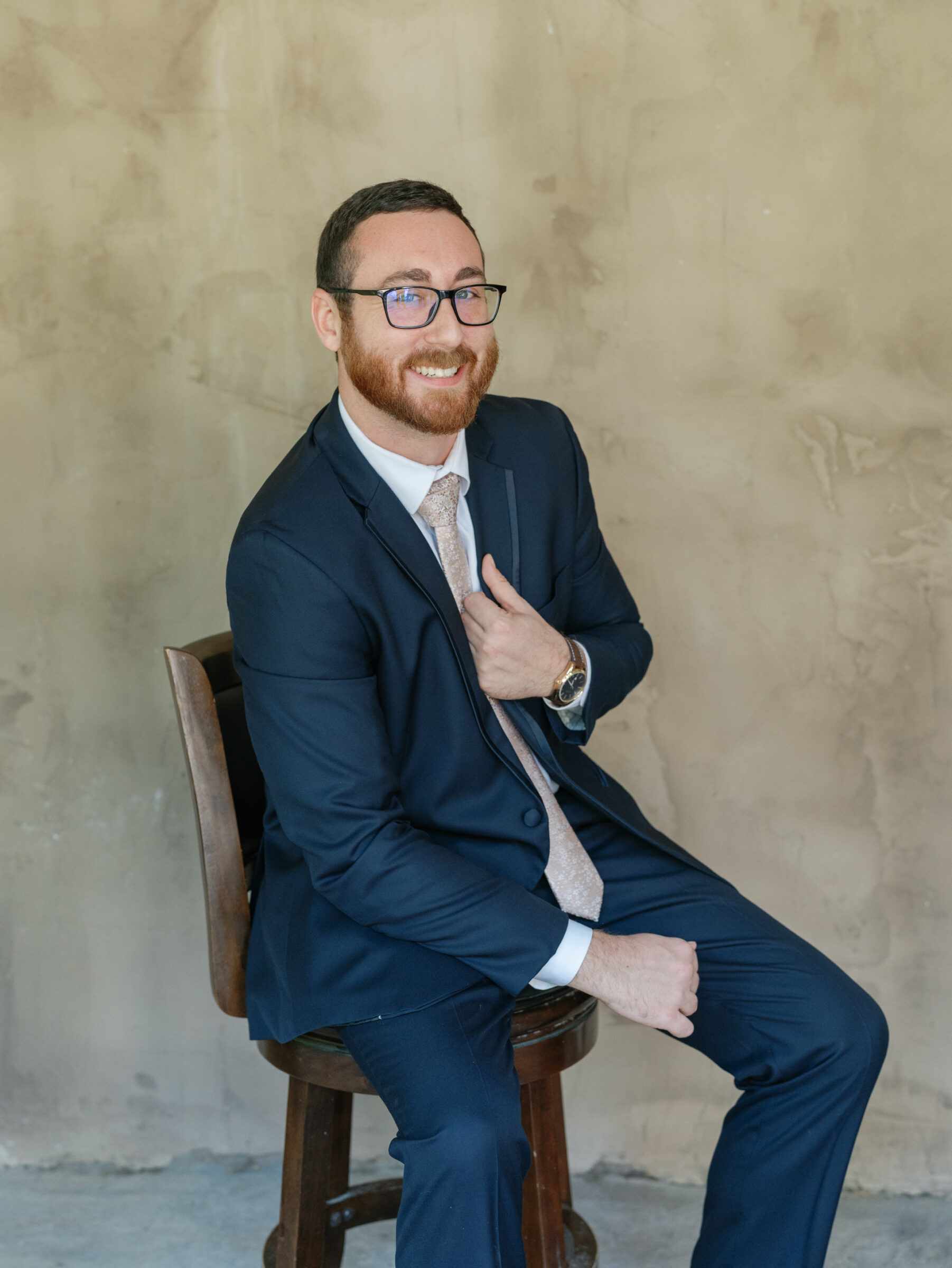 Groom in a navy suit smiling during portraits at Ashton Creek Vineyards wedding in Chester VA.