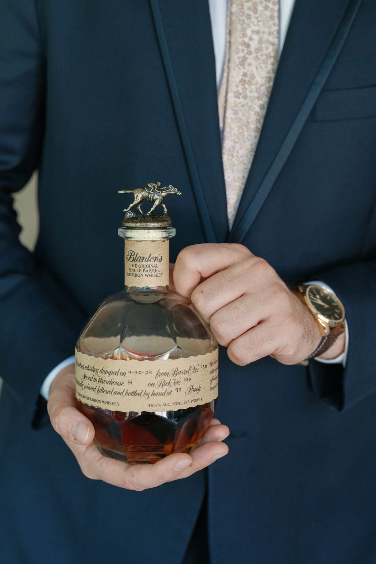 Groom holding a bottle of Blanton’s bourbon during wedding preparations.