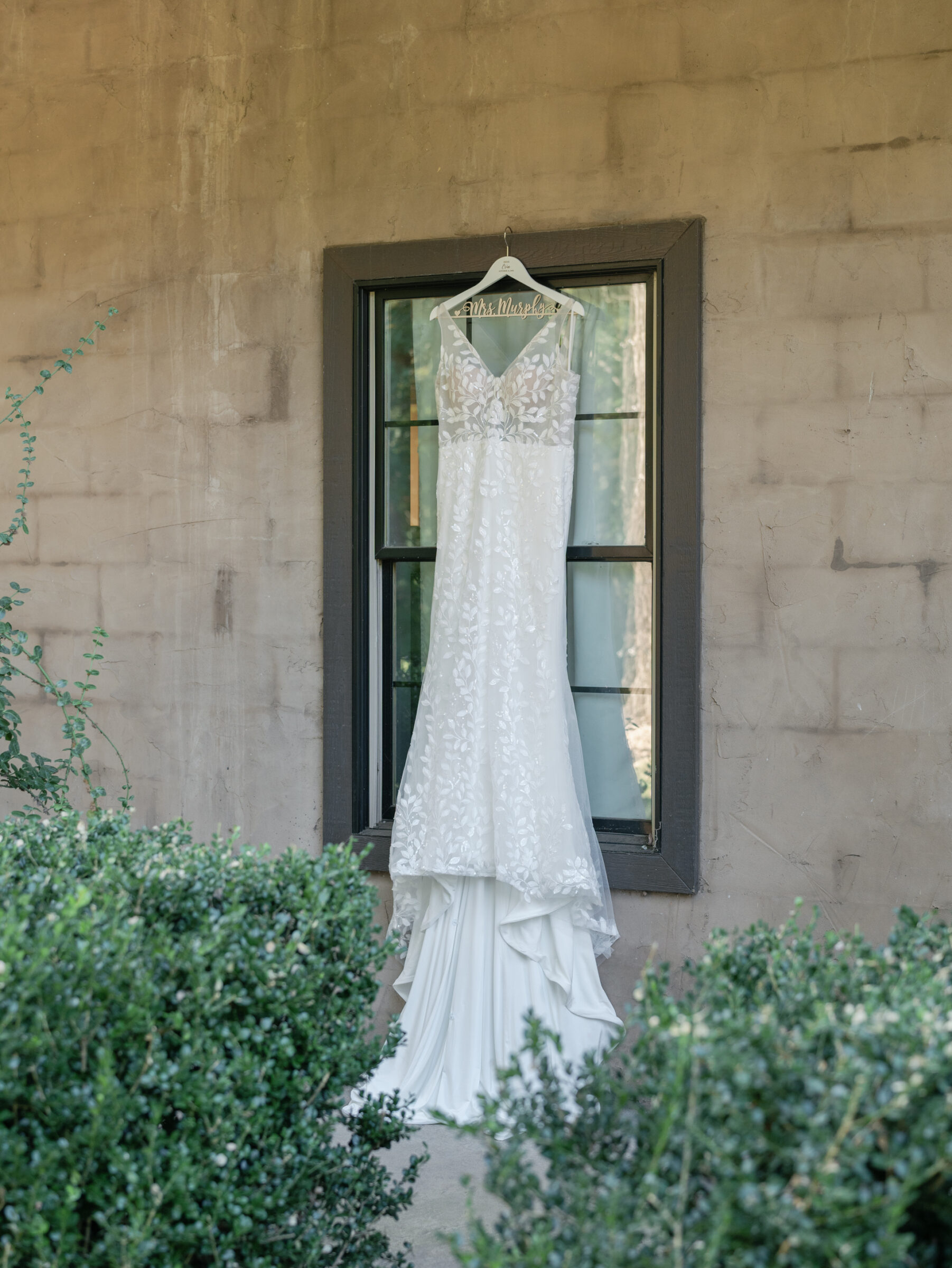 Wedding dress hanging outside against rustic stone walls at Ashton Creek Vineyards in Chester VA before the ceremony.