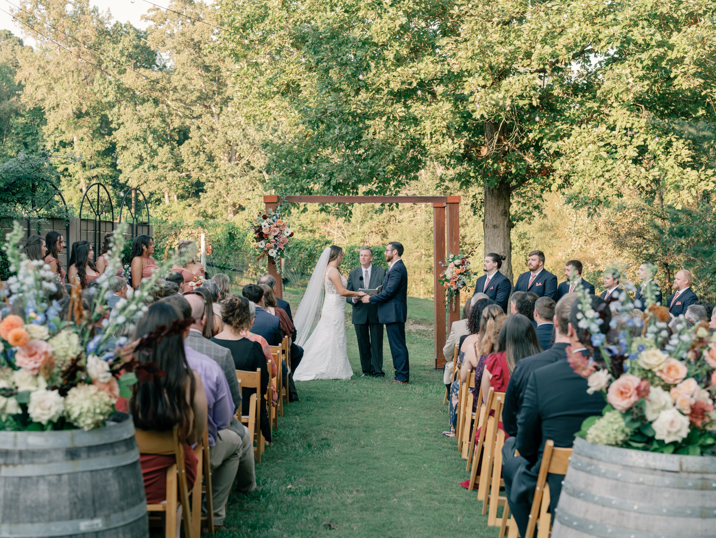 Bride and groom exchanging vows during an outdoor wedding ceremony at Ashton Creek Vineyards in Chester VA surrounded by family and friends.