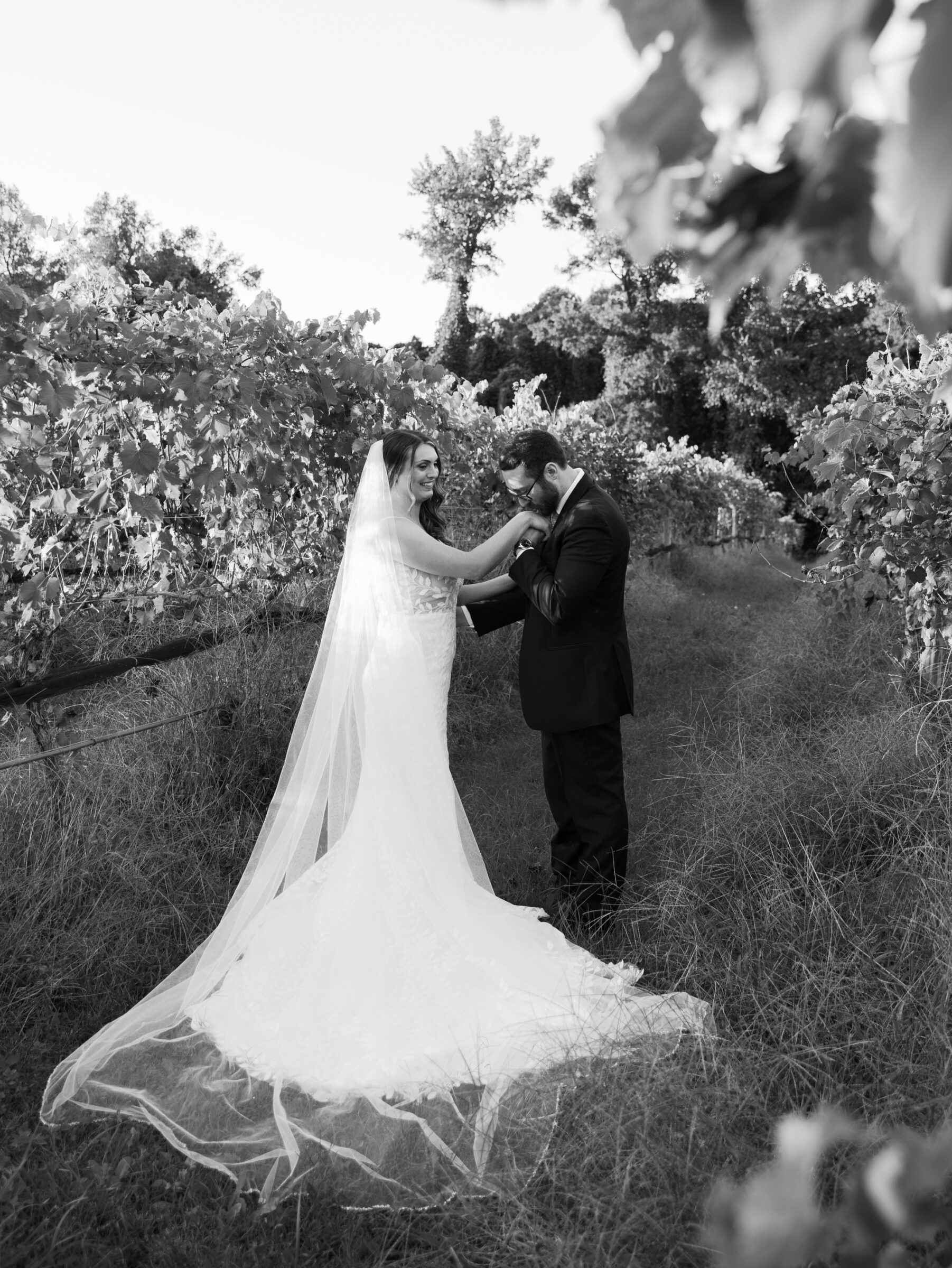 Black and white wedding portrait of bride and groom in the vineyard at Ashton Creek Vineyards, sharing a tender moment among the vines.