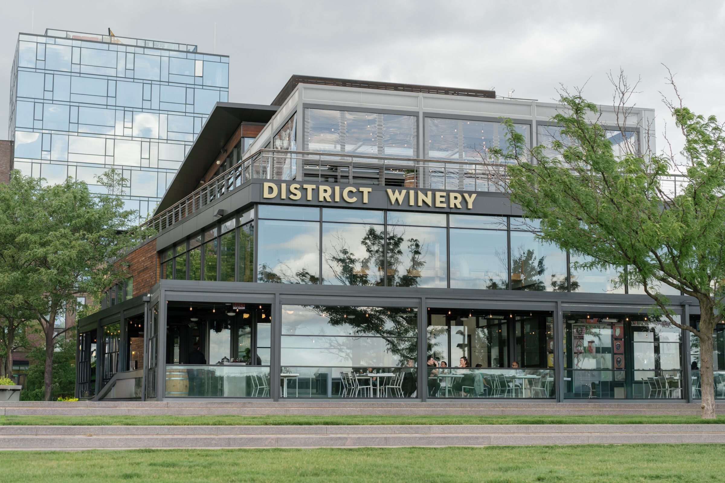 Exterior view of District Winery in Washington DC, a modern waterfront wedding venue with glass walls and terrace spaces, perfect for a District Winery wedding.