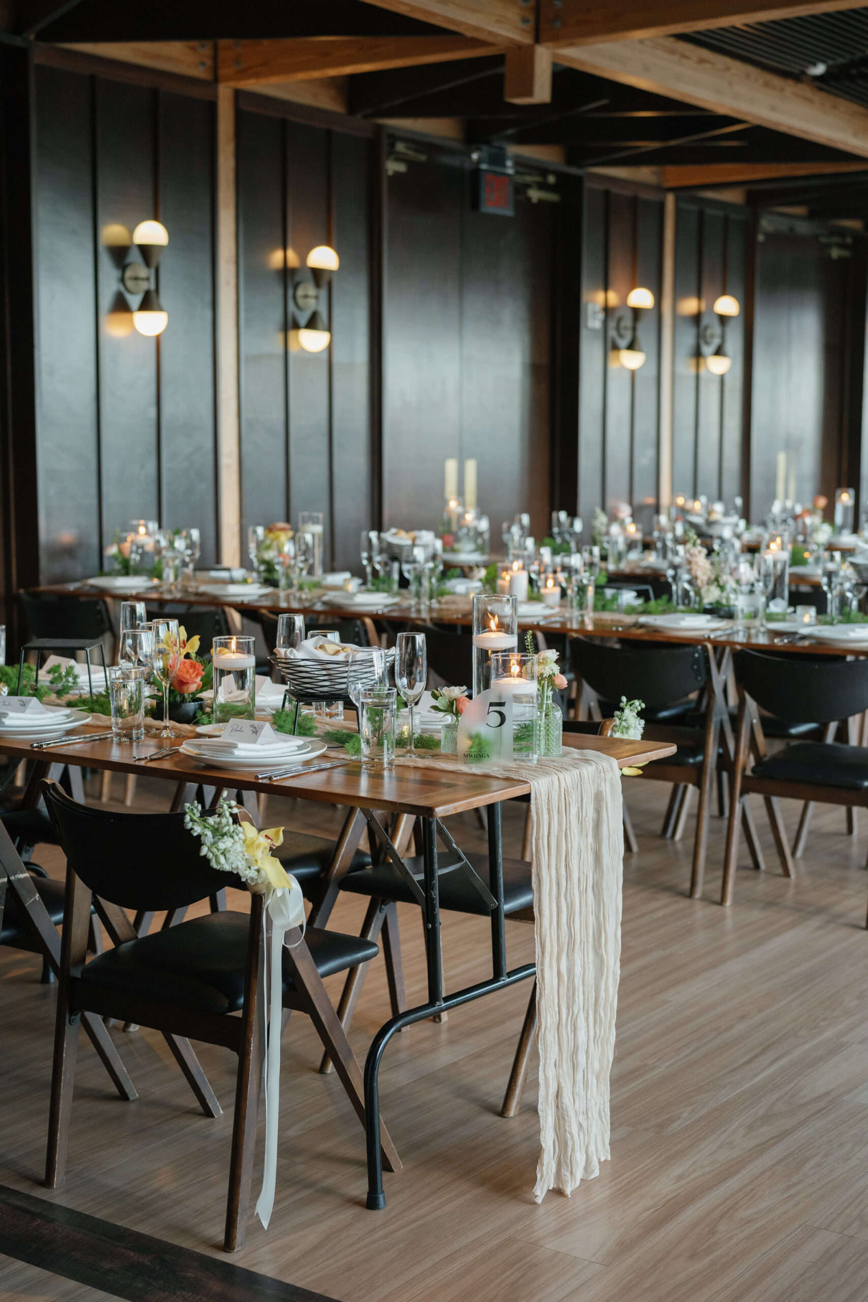 District Winery wedding reception setup in Washington DC with long wooden tables, greenery, candles, and floral centerpieces creating a modern elegant design.