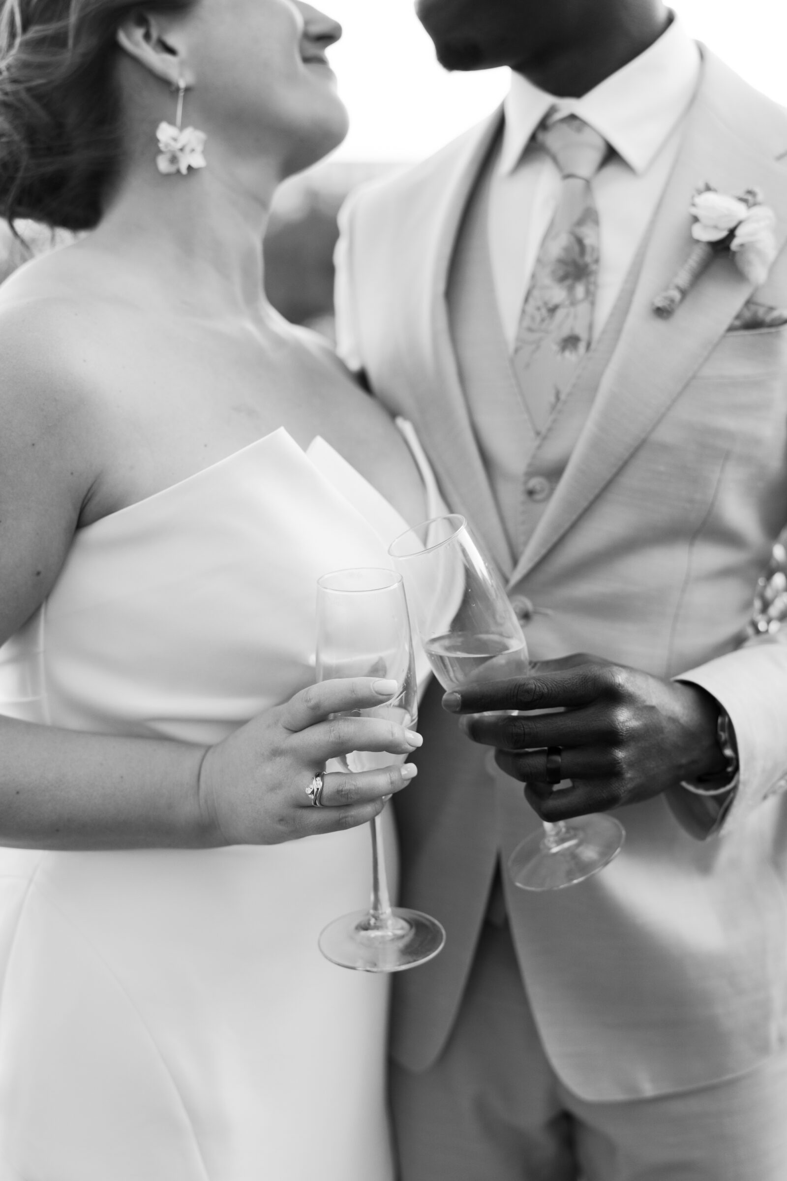 Black and white wedding photo of bride and groom clinking champagne glasses during their District Winery wedding in Washington DC.
