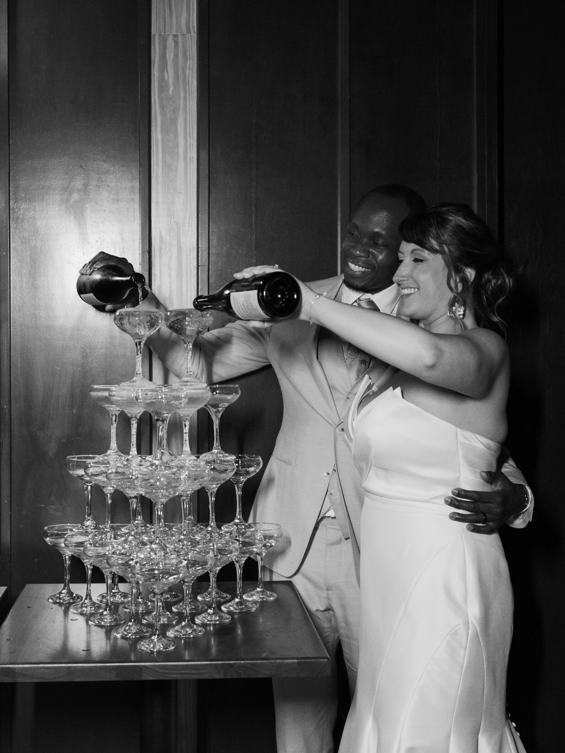 Bride and groom pouring champagne into a tower of coupe glasses during their District Winery wedding reception in Washington DC.
