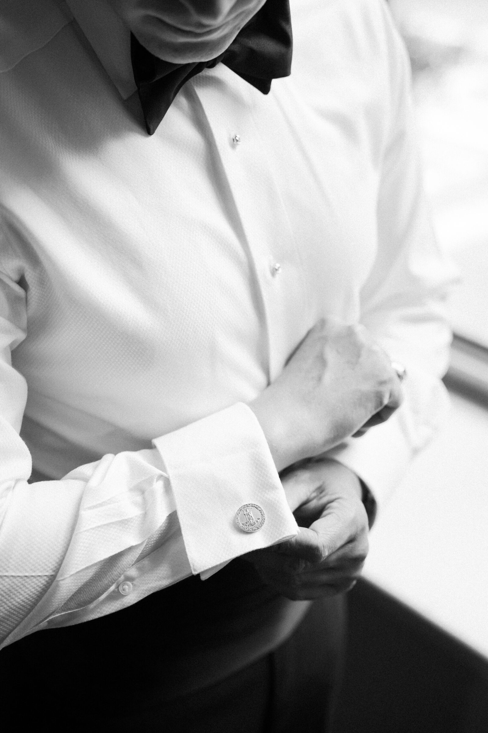 Black and white photo of a groom adjusting his cufflinks while getting ready for his wedding in Richmond VA.