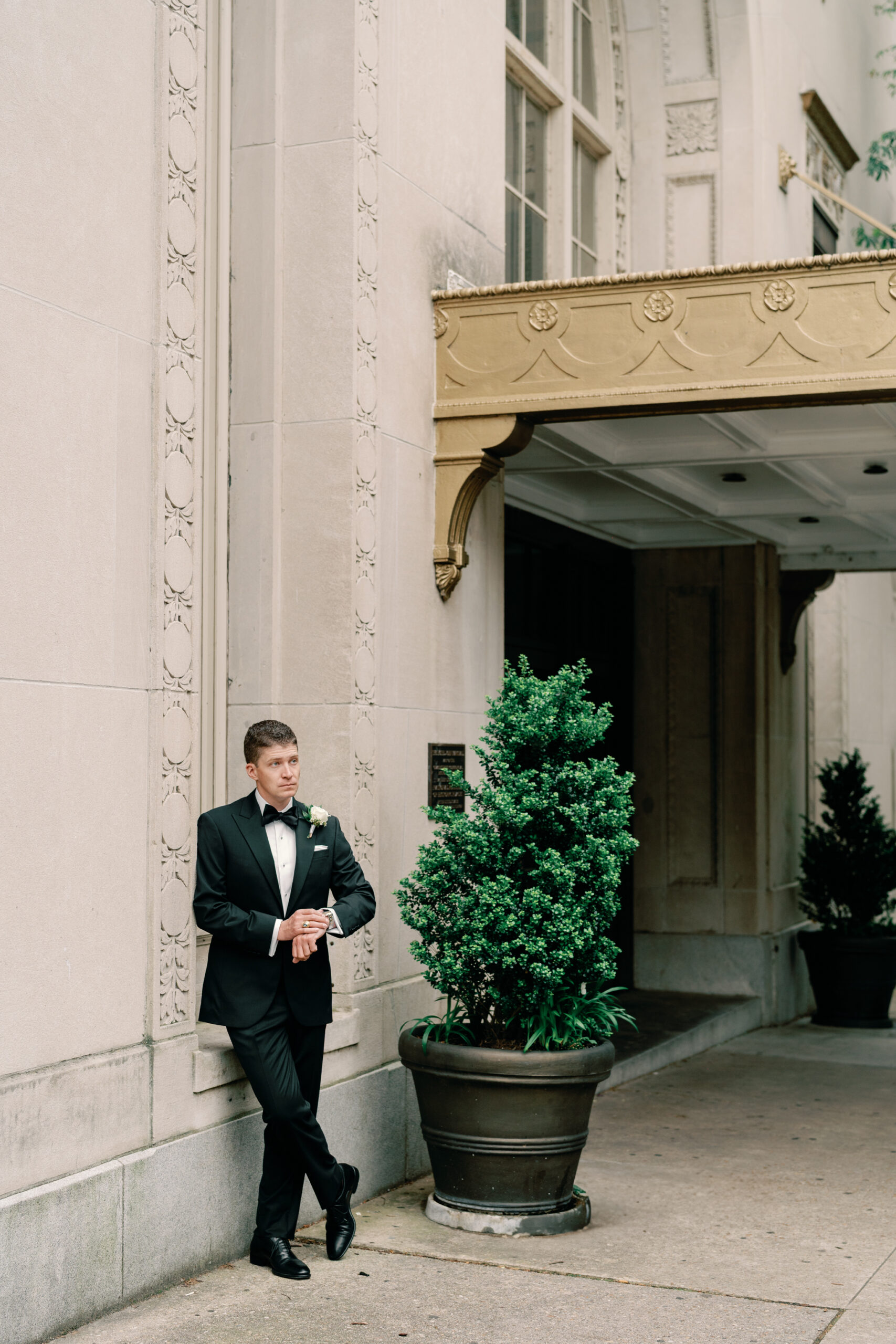 Groom in a black tuxedo standing outside the Hotel John Marshall before his Richmond VA wedding.